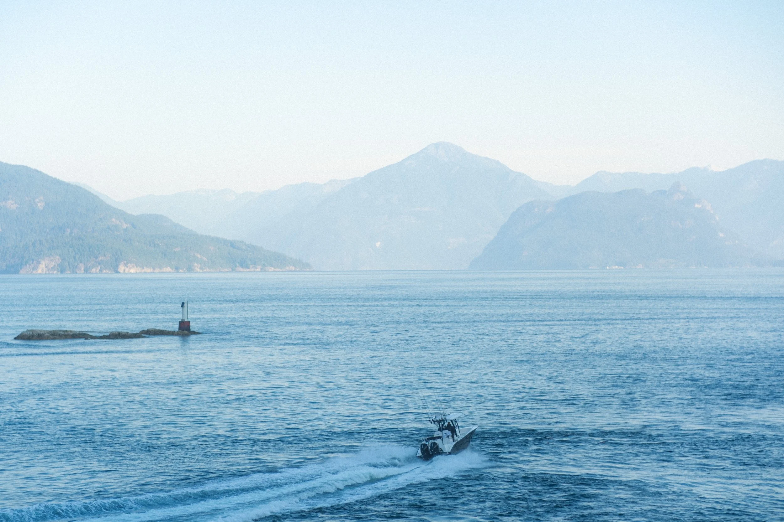 A boat moving across a body of water with mountains in the distance.