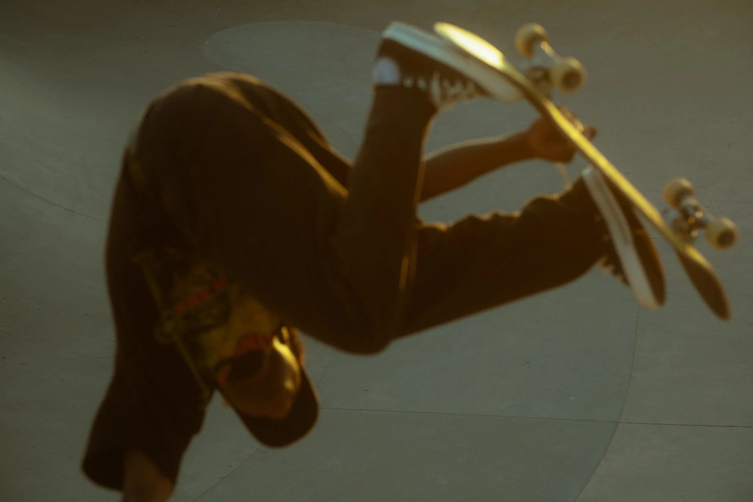 A person holding a skateboard indoors, with the skateboard tilted and the person's hand gripping it.