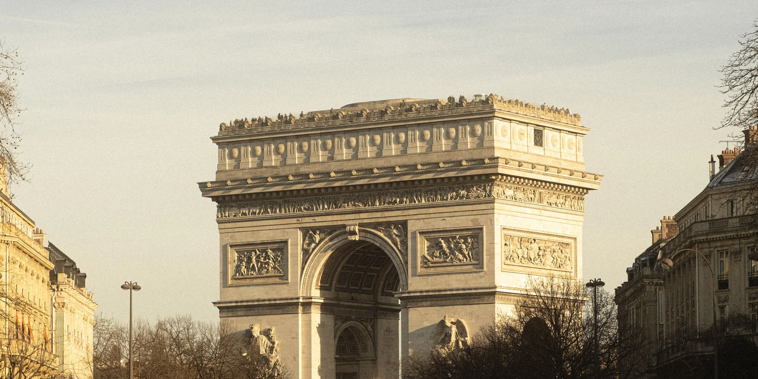 Paris Arc de Triomphe with buildings and trees on a clear day