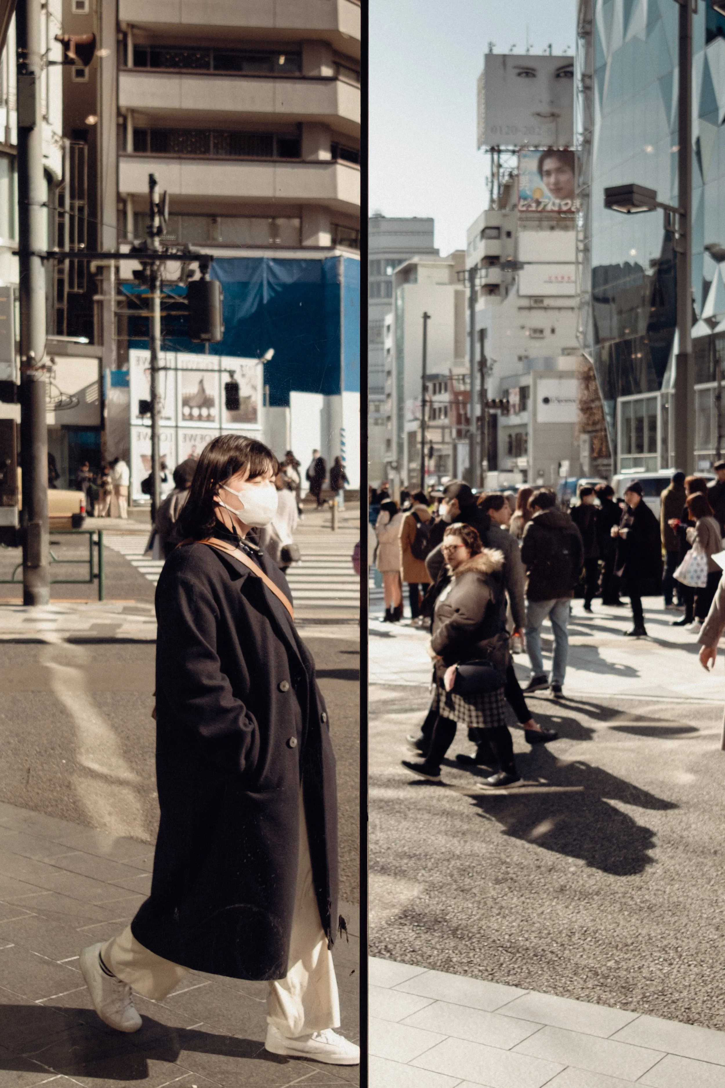 A city street scene divided into two sections showing different perspectives. On the left, a woman wearing a mask, black coat, and white sneakers stands with her hands in her pockets while crossing the street. On the right, a busy crosswalk filled wi