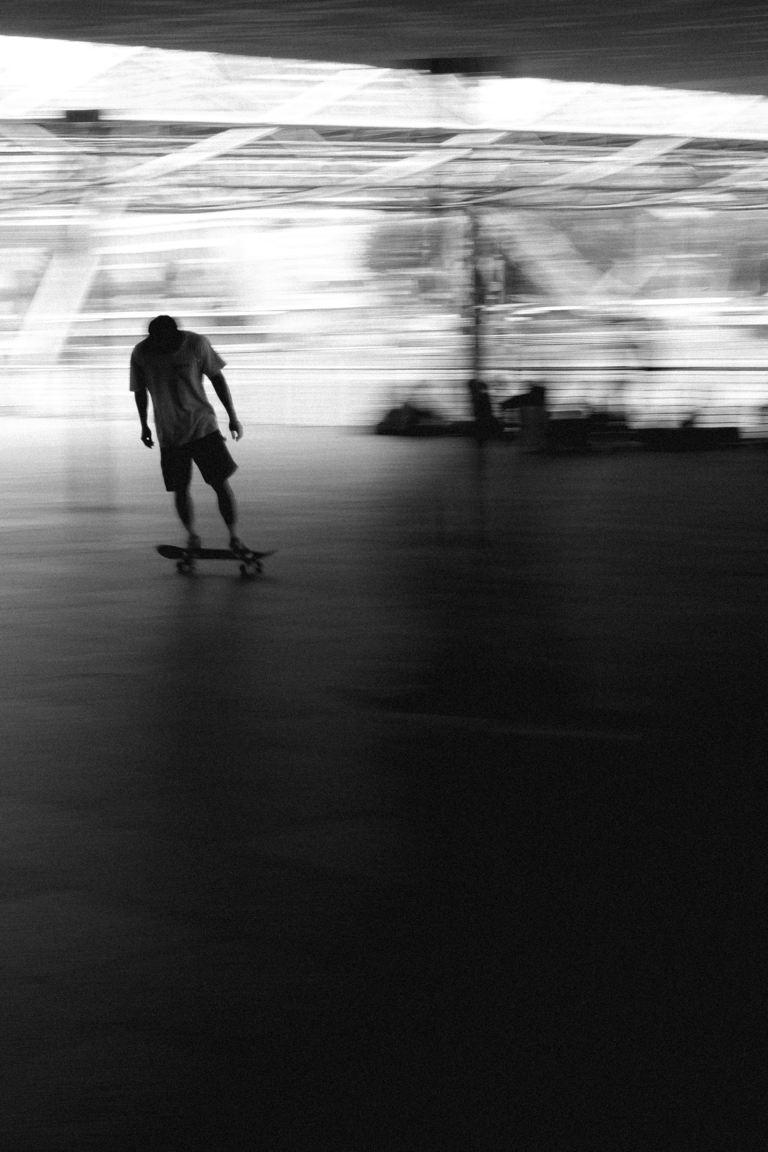 A person skateboarding indoors in front of a metal fence, with blurred background and motion effects.