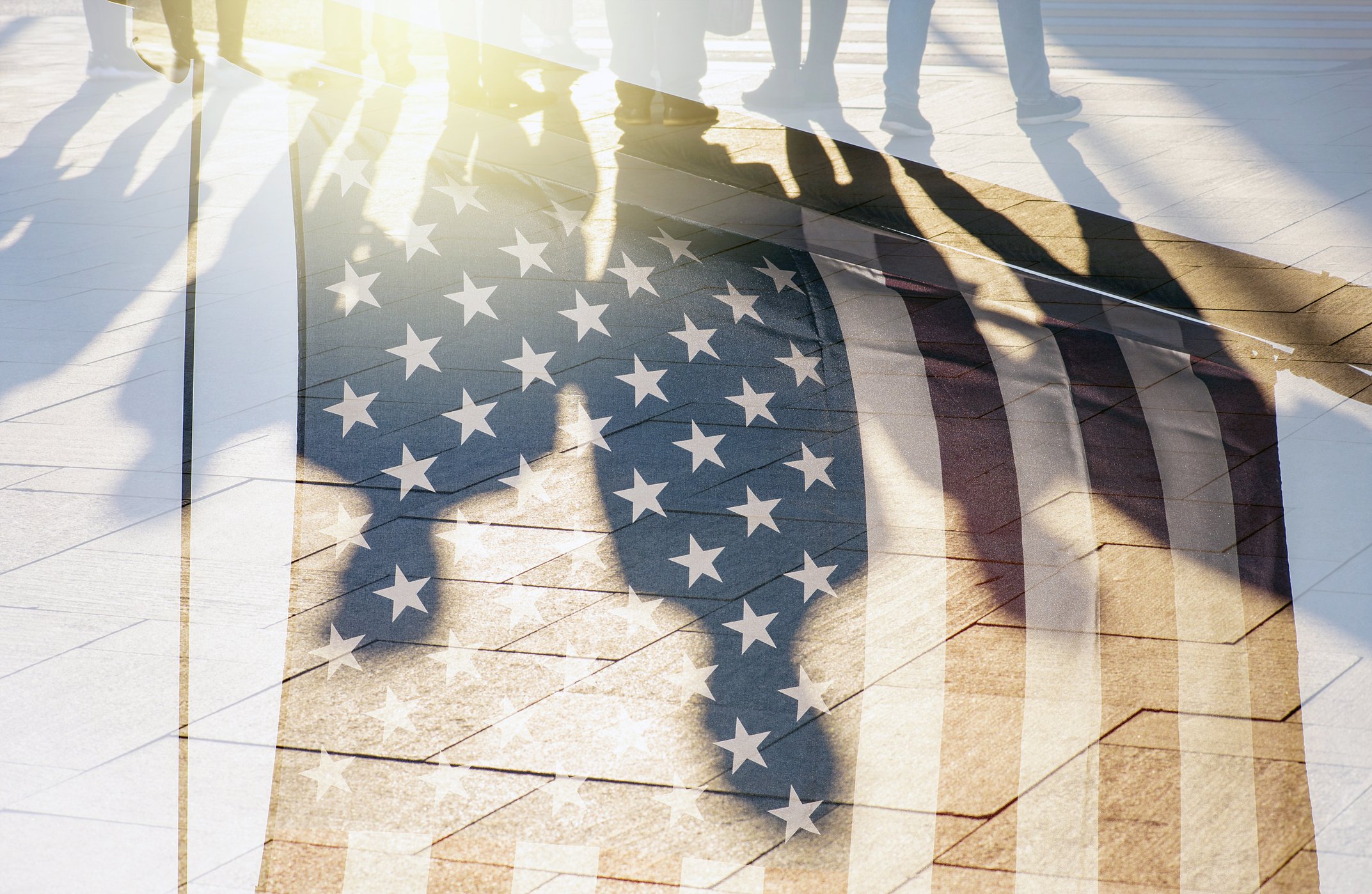 Shadows of people walking on a tiled floor with an overlay of the American flag and the United States Capitol dome.
