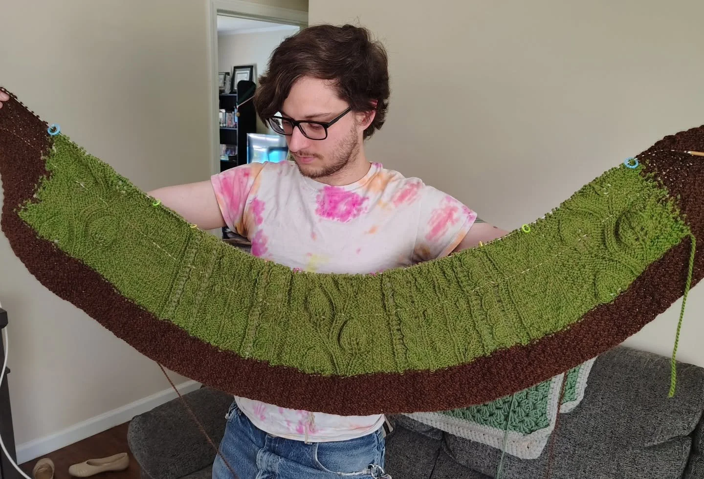 My sweet husband holding up my blanket I'm making for his gma! This is 2 skeins of the green yarn.