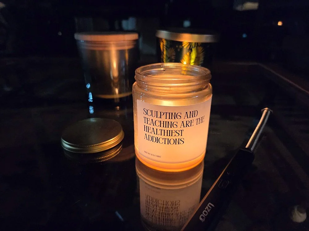 The message on the lit candle boldly declares that sculpting and teaching are the best addictions.