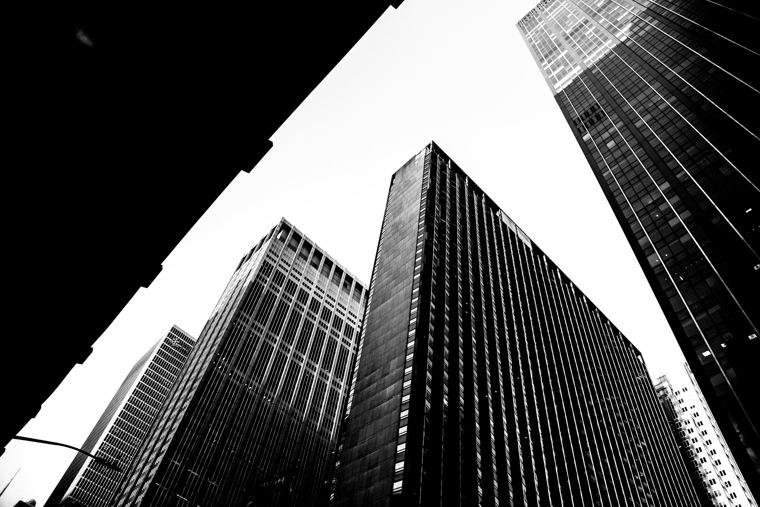 Black and white photo of skyscrapers from a low angle looking up in a city.