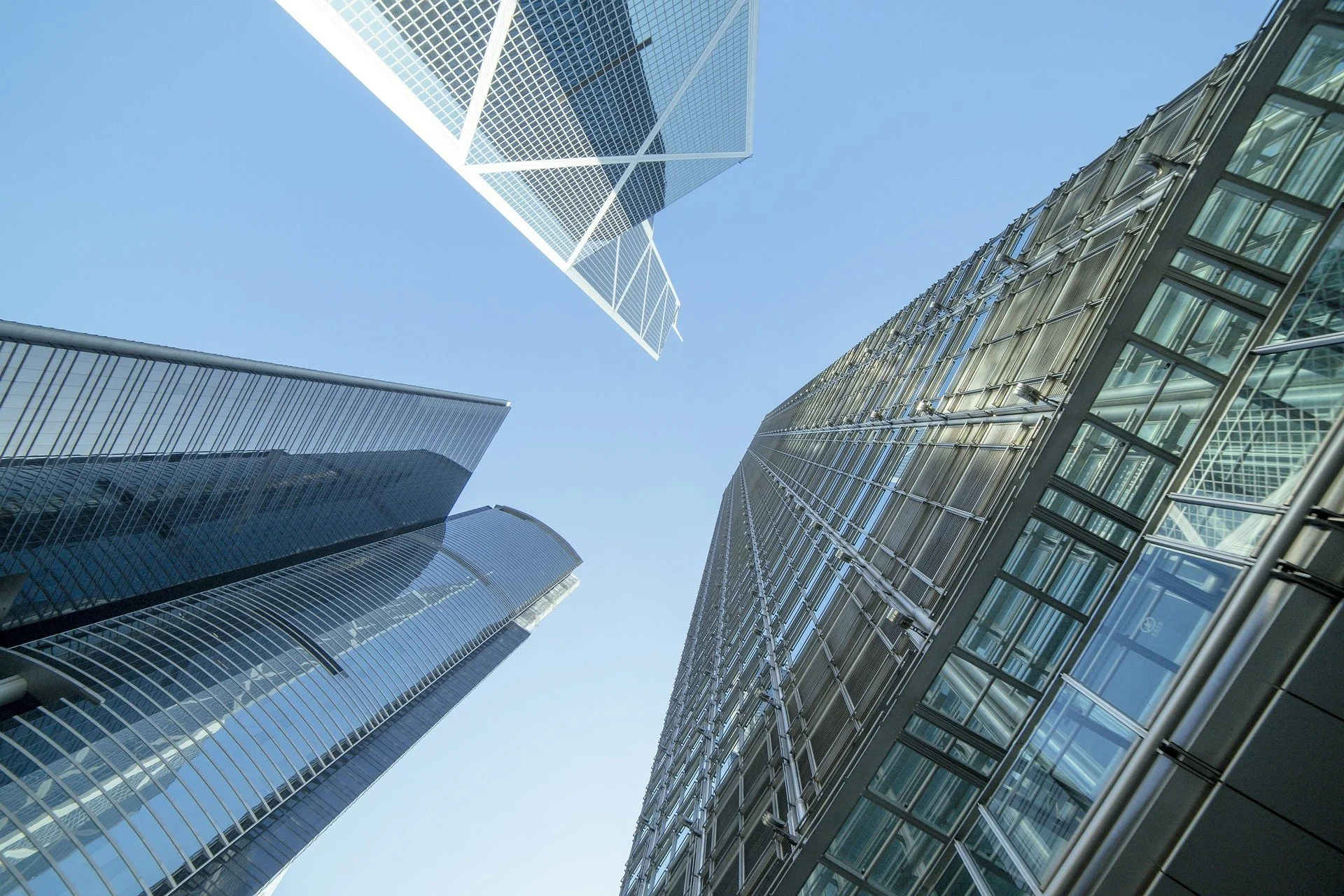 Looking up at modern glass skyscrapers against a clear blue sky.