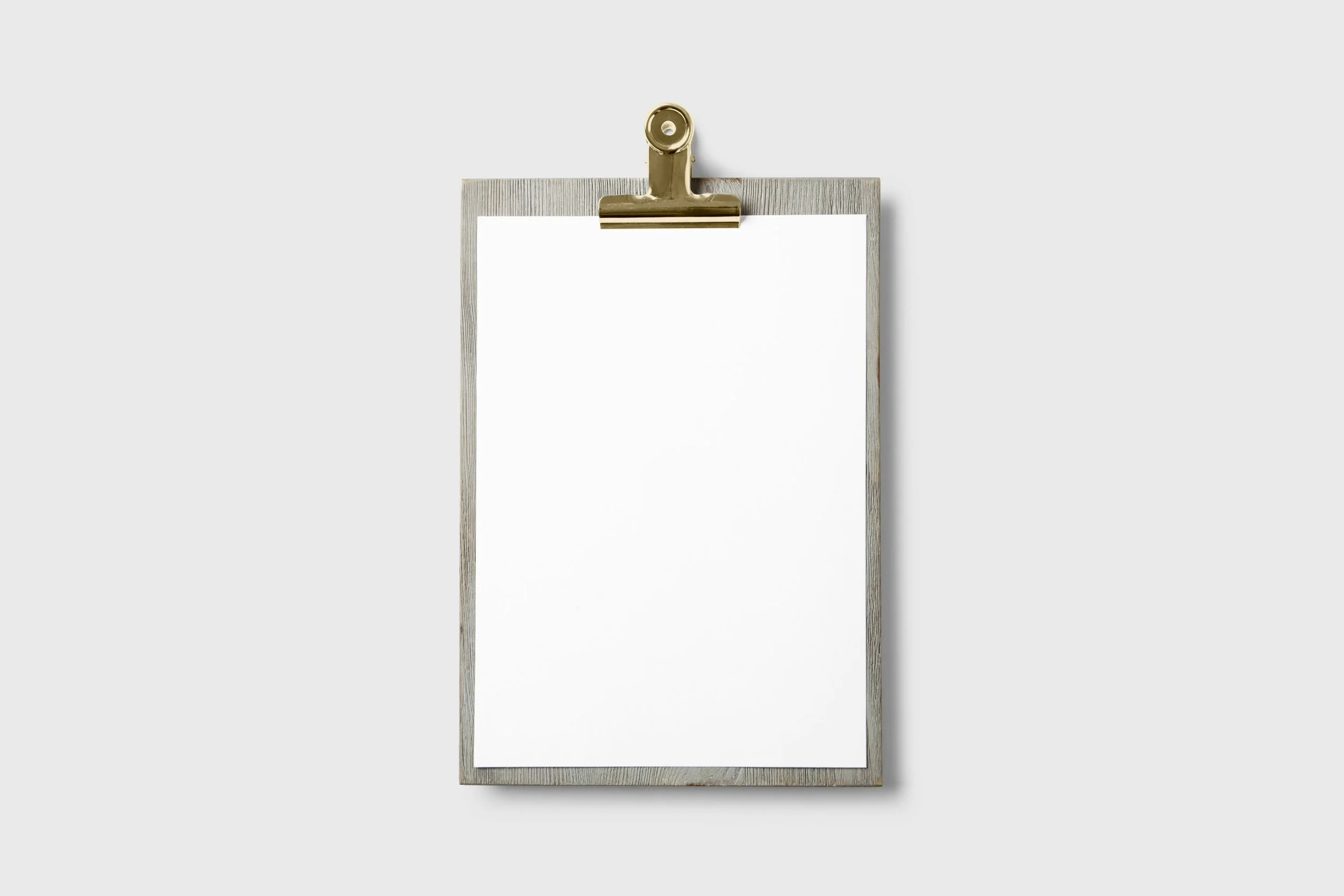 Clipboard with a blank white sheet of paper attached, mounted on a wall.