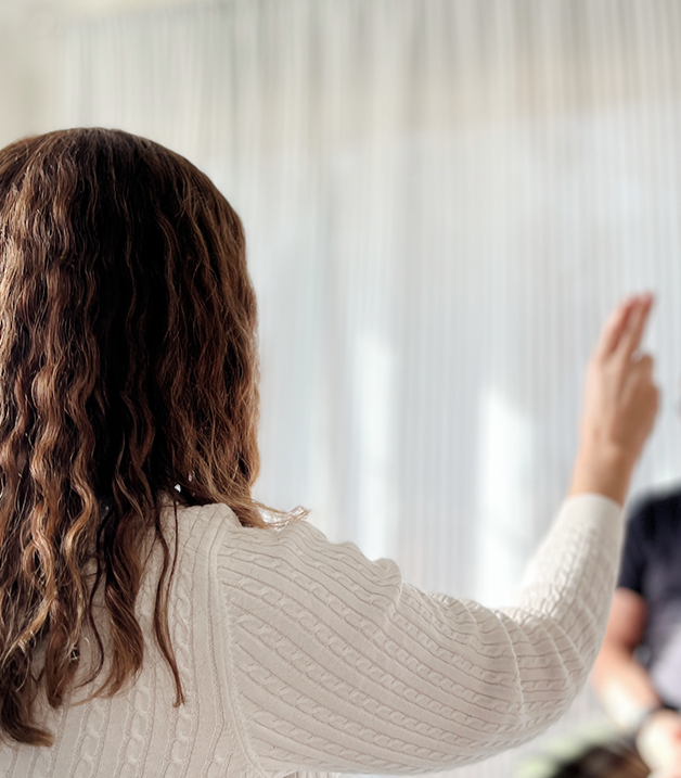 Therapist with curly brown hair preforming an EMDR hand movement. In profile in a bright room.