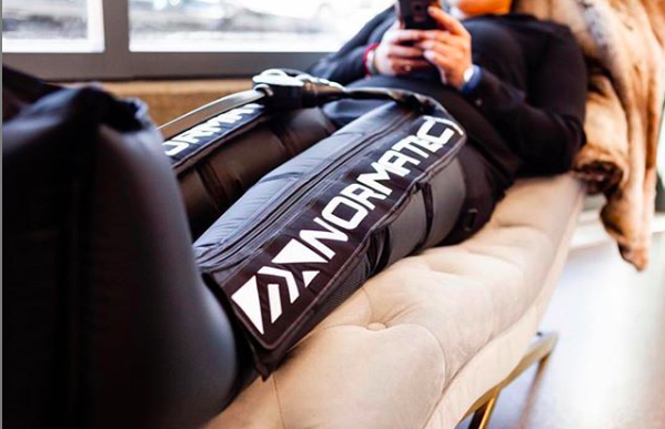 Person lying on a couch using compression sleeve. NormaTech