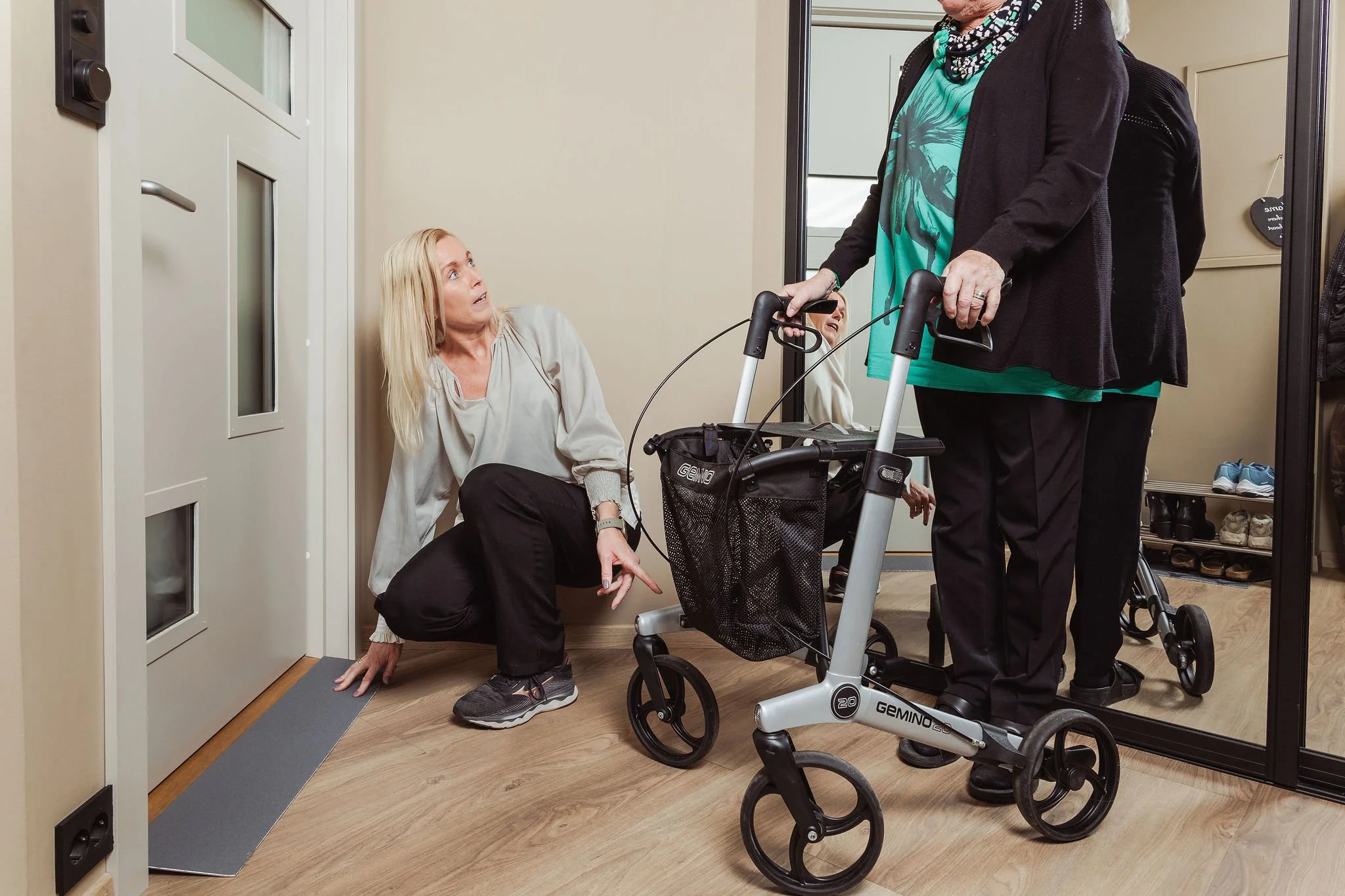 Ergoterapeut tilpasser hjelpemiddel i hjemmet ved å vise terskeleliminator for tryggere ferdsel med rullator