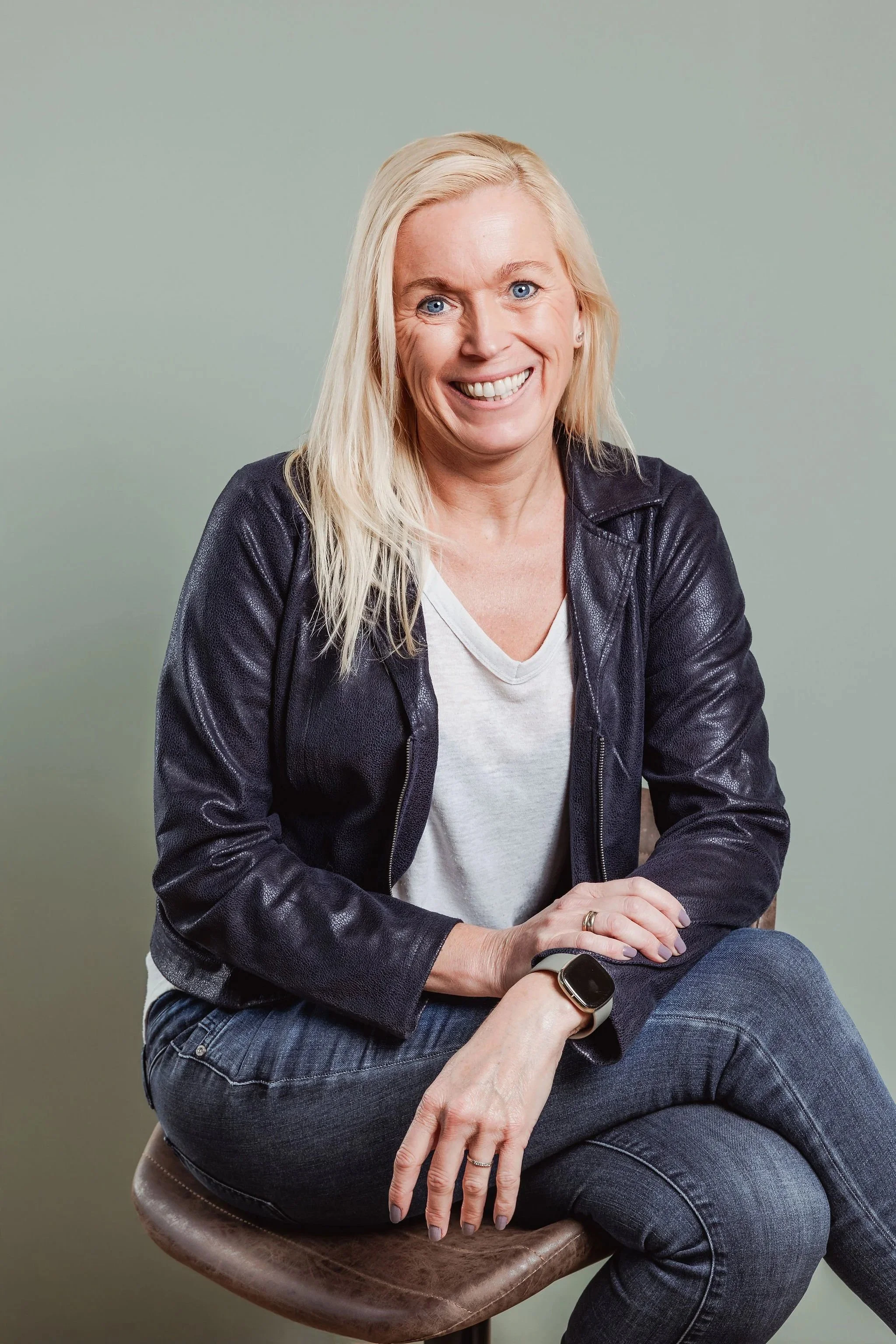 Portrett av Kristin Tverberg, grunnlegger av Ergoressurs, sittende på en krakk i profesjonelt portrettmiljø.