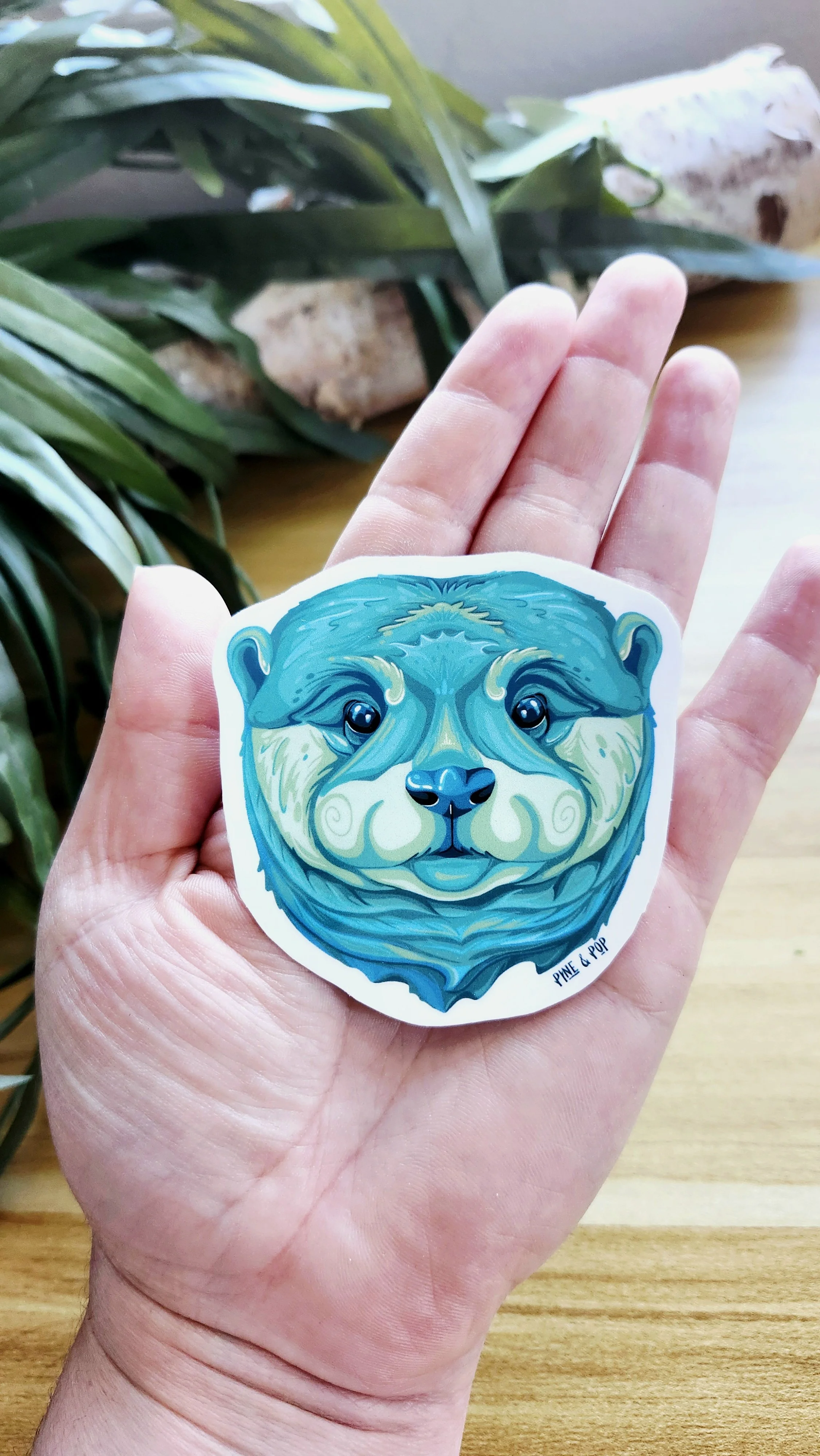 hand holding otter face sticker