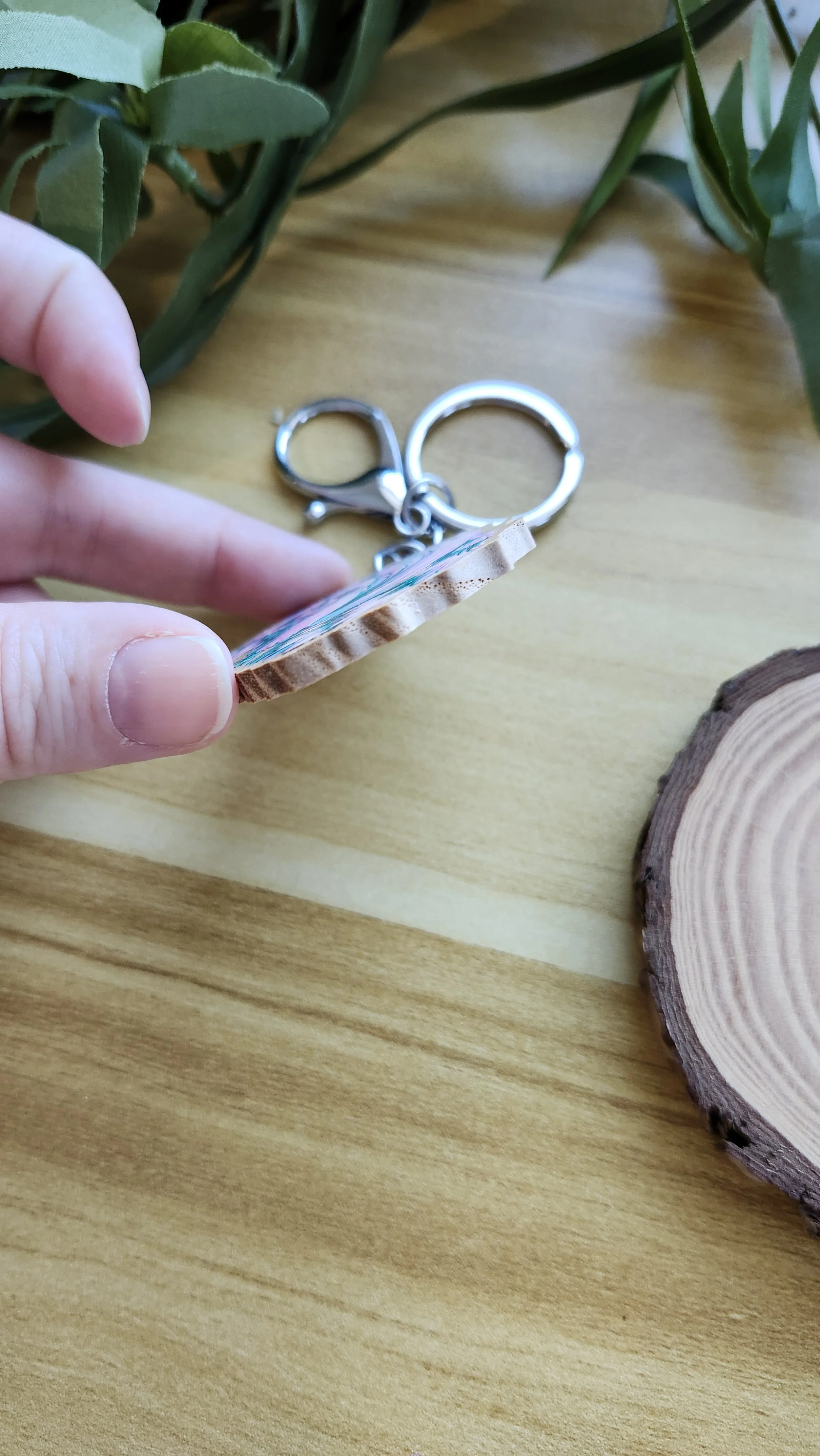hand holding keychain to show the wooden edge and thickness