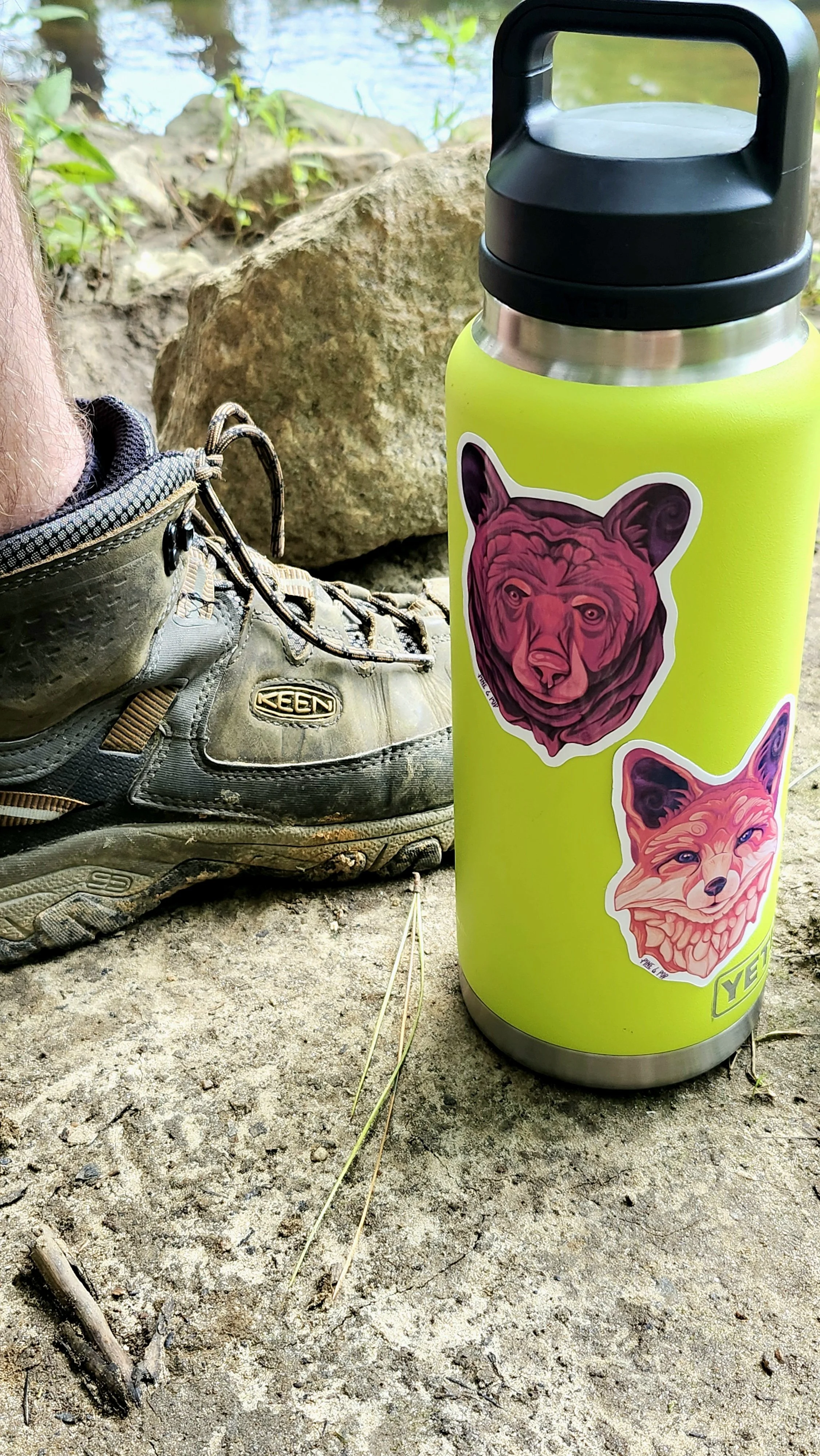 the bear face sticker along with other stickers on a water bottle in the outdoors