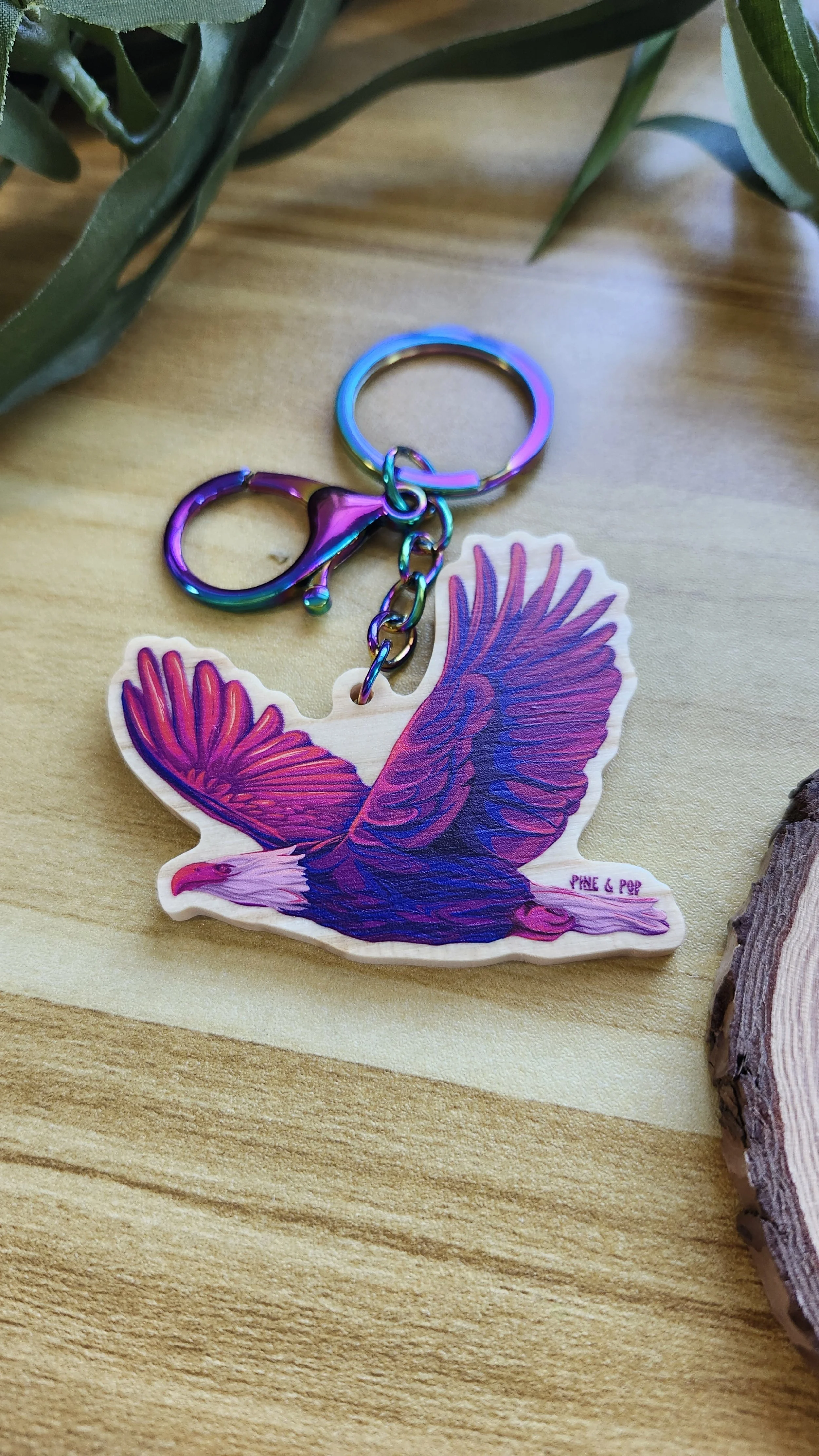 wooden keychain of a bald eagle in flight with bold purple and pink colors