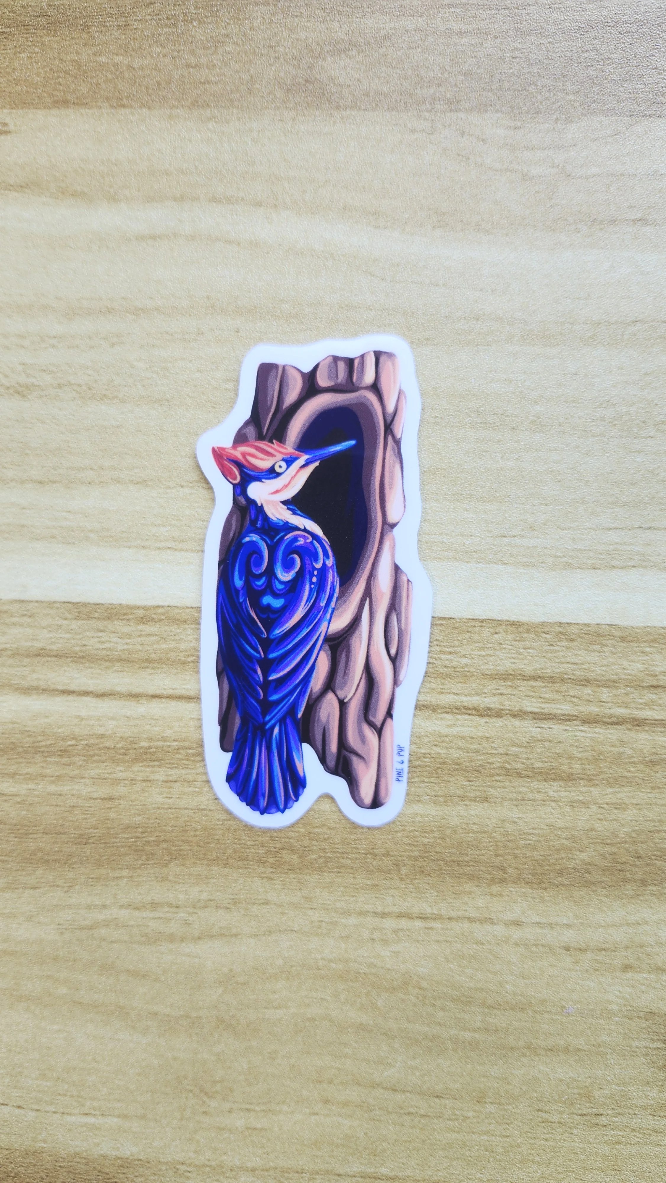 vinyl sticker of pileated woodpecker sitting next to a hole in the tree created using bold colors