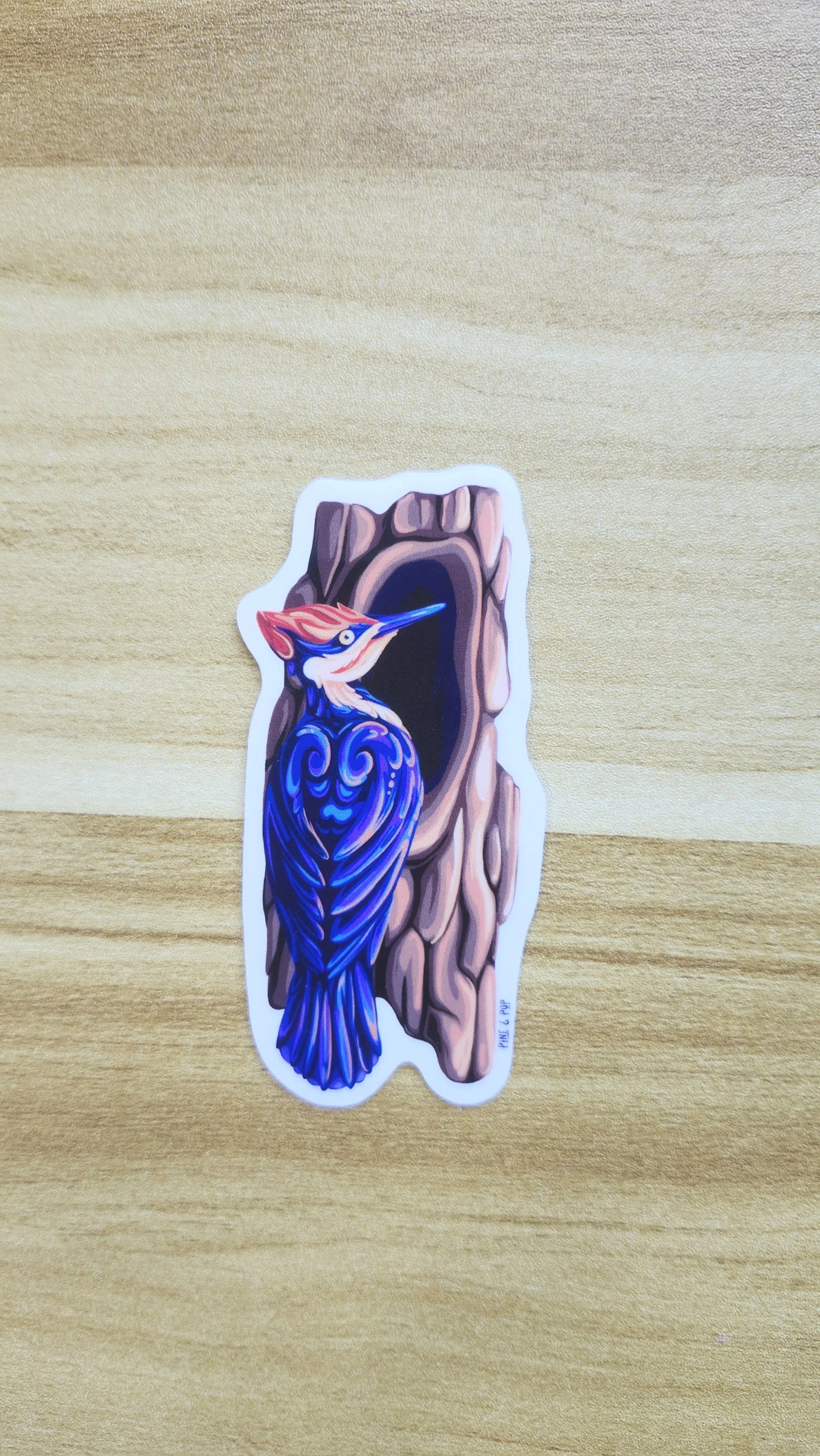 vinyl sticker of pileated woodpecker sitting next to a hole in the tree created using bold colors