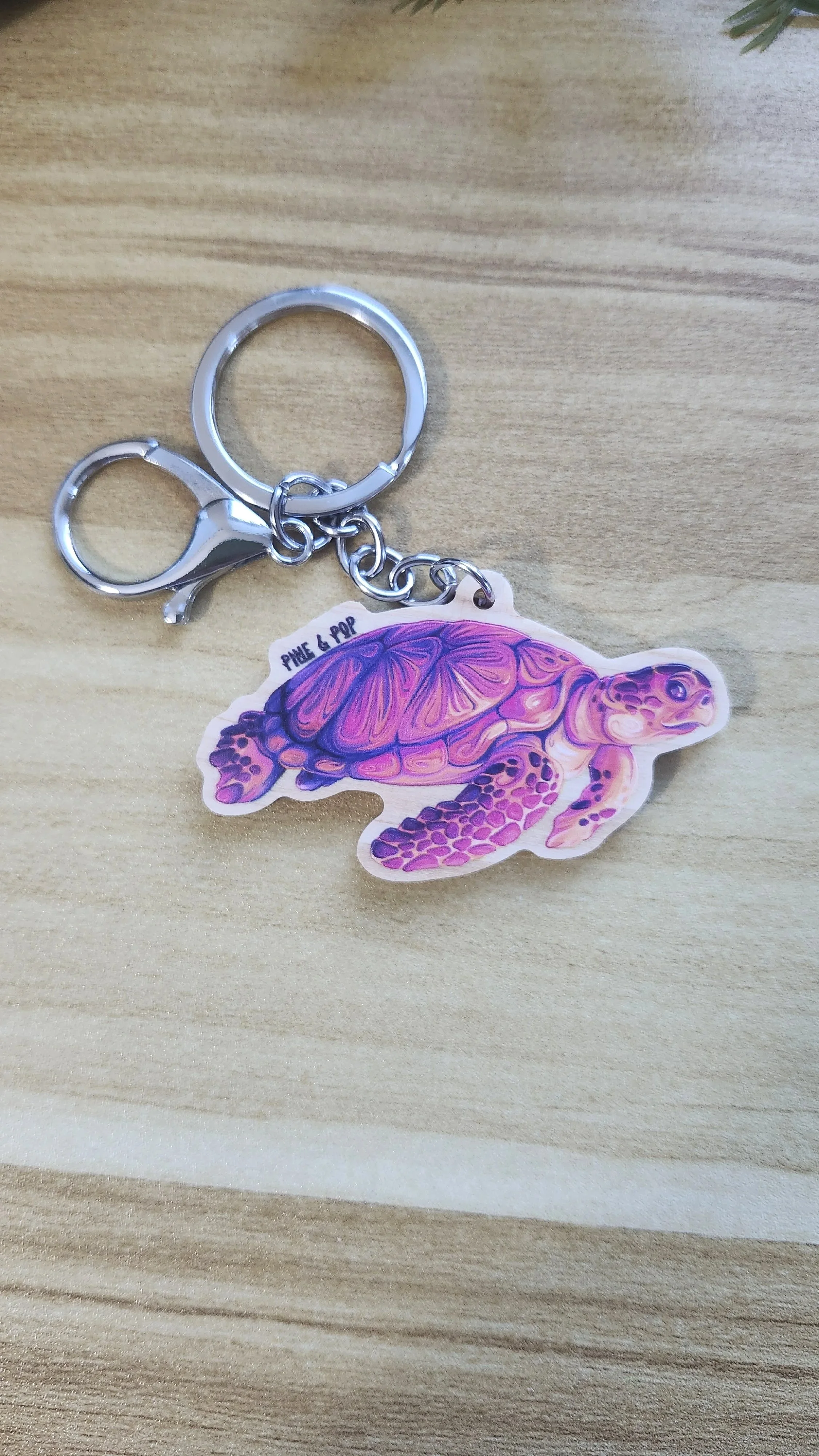wooden keychain of loggerhead sea turtle made up of yellow, orange, pink, and purple colors