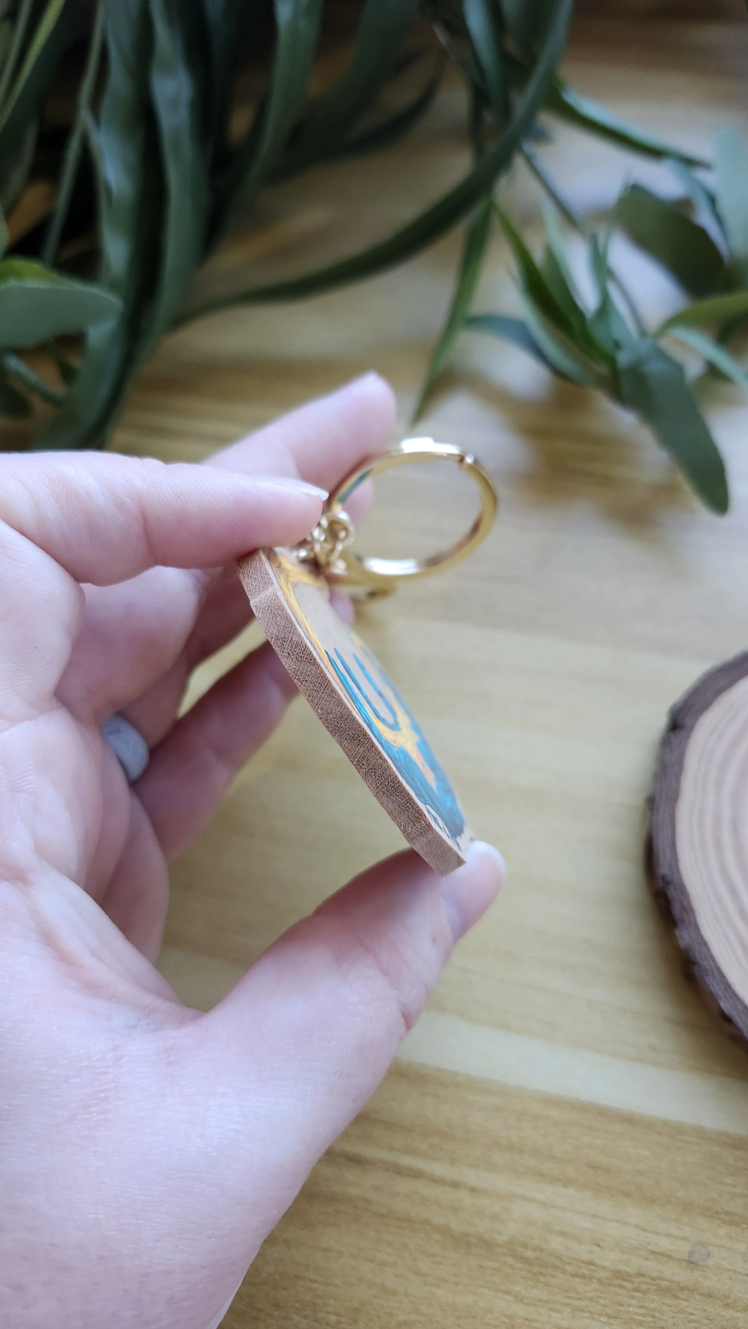 hand holding the wooden keychain to show the thickness of the wooden edge