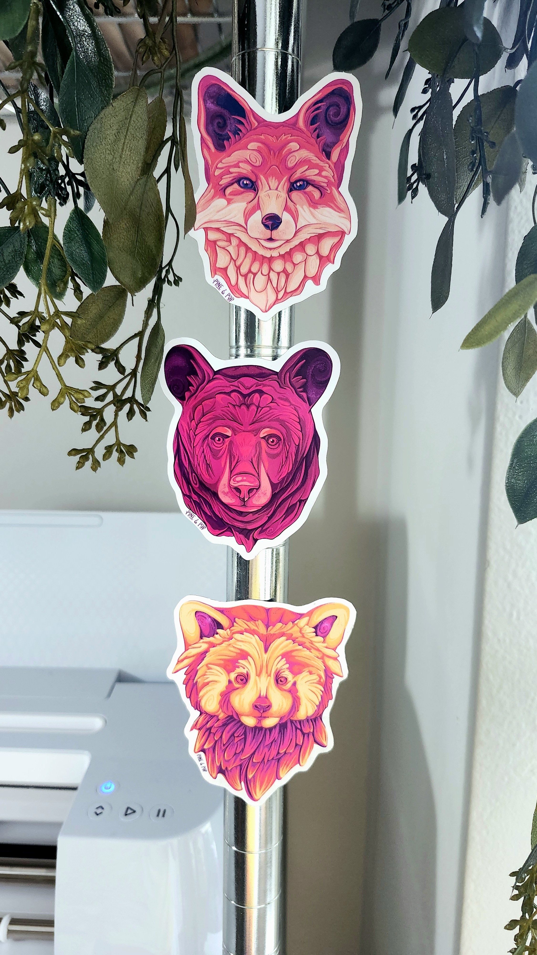 a bear face magnet, a fox face magnet, and a red panda magnet stuck on a metal pole