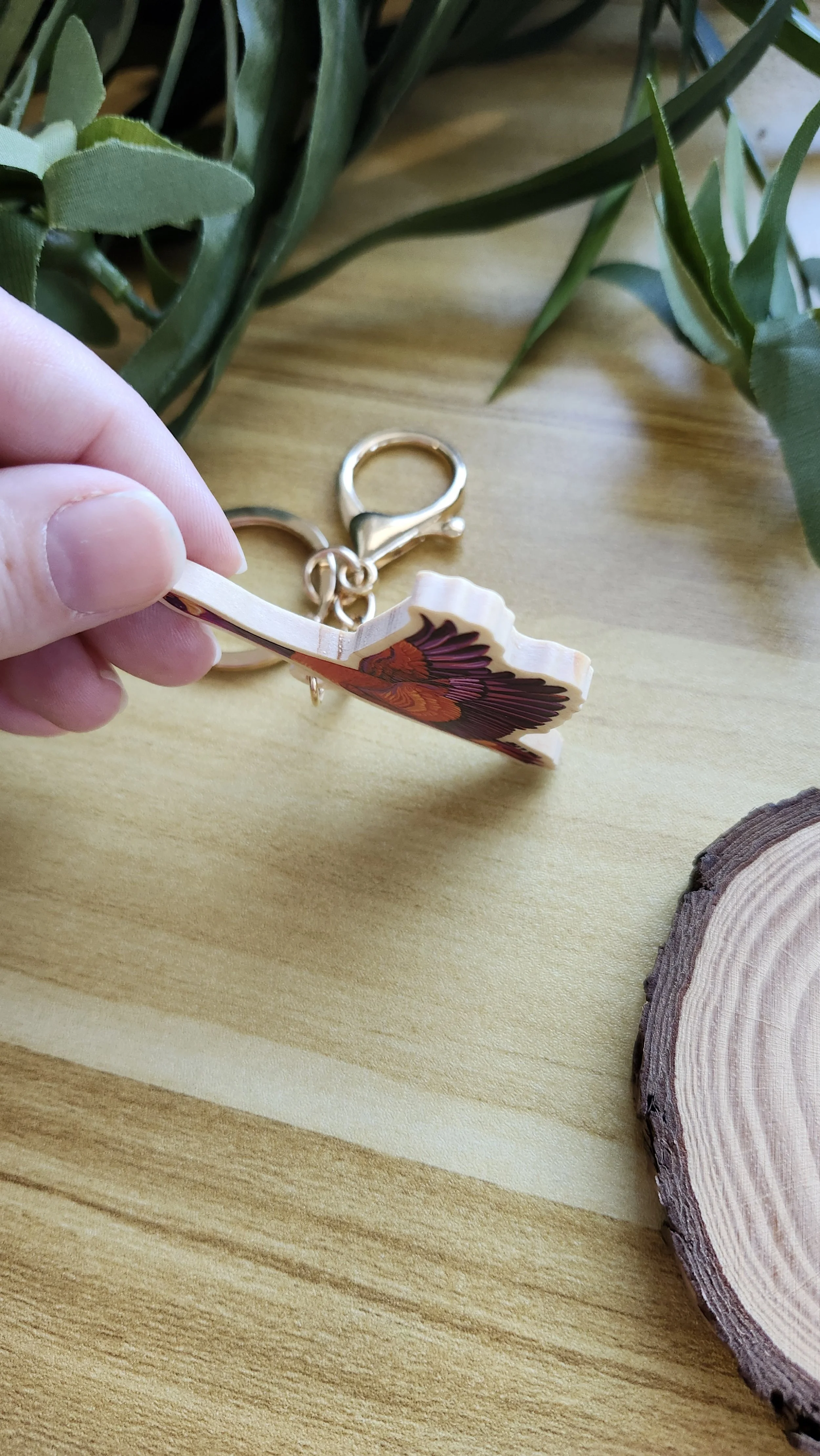hand holding keychain to the side to show the wooden edge and thickness