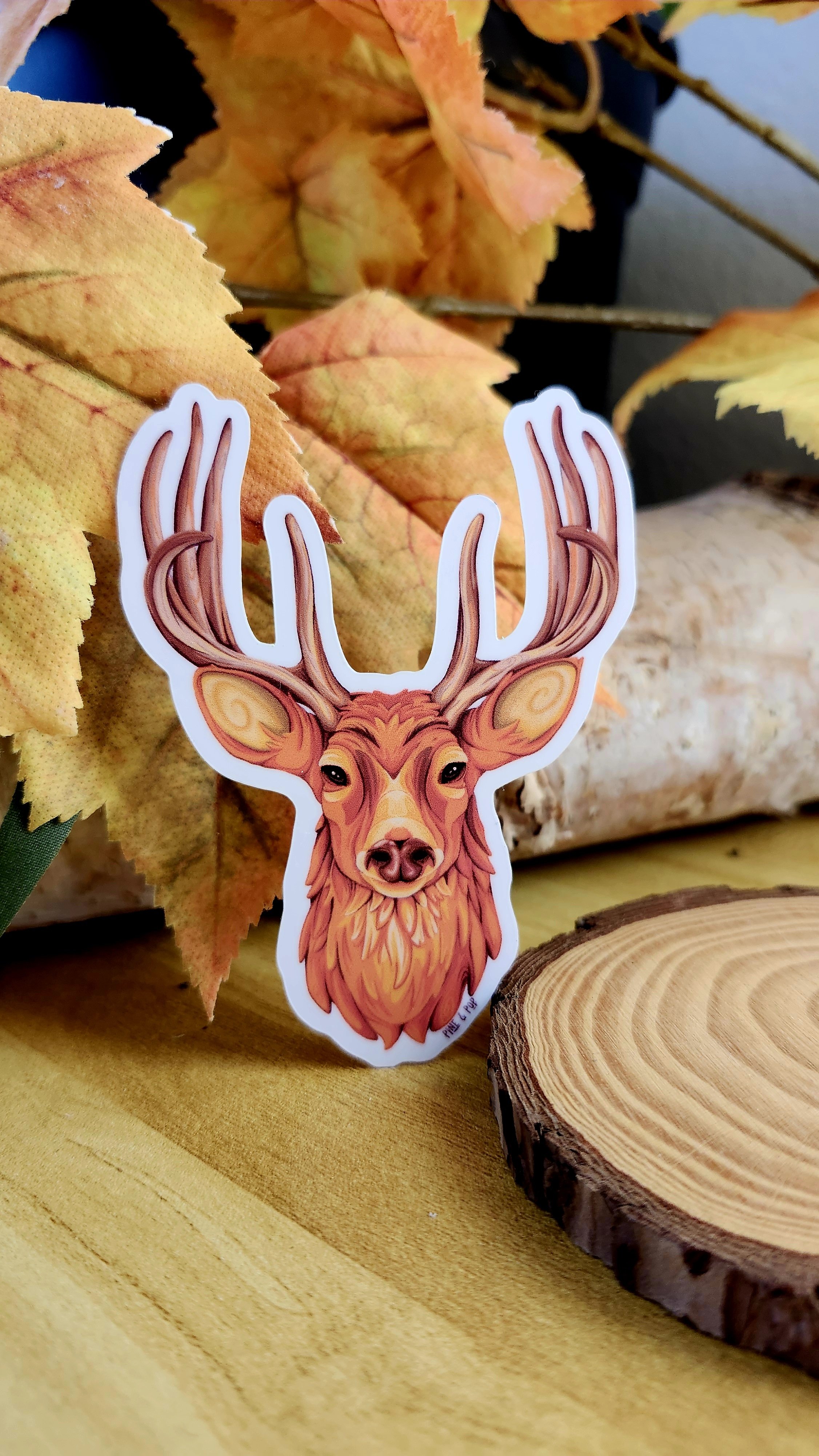 sticker of deer head with antlers, leaning against a tree section