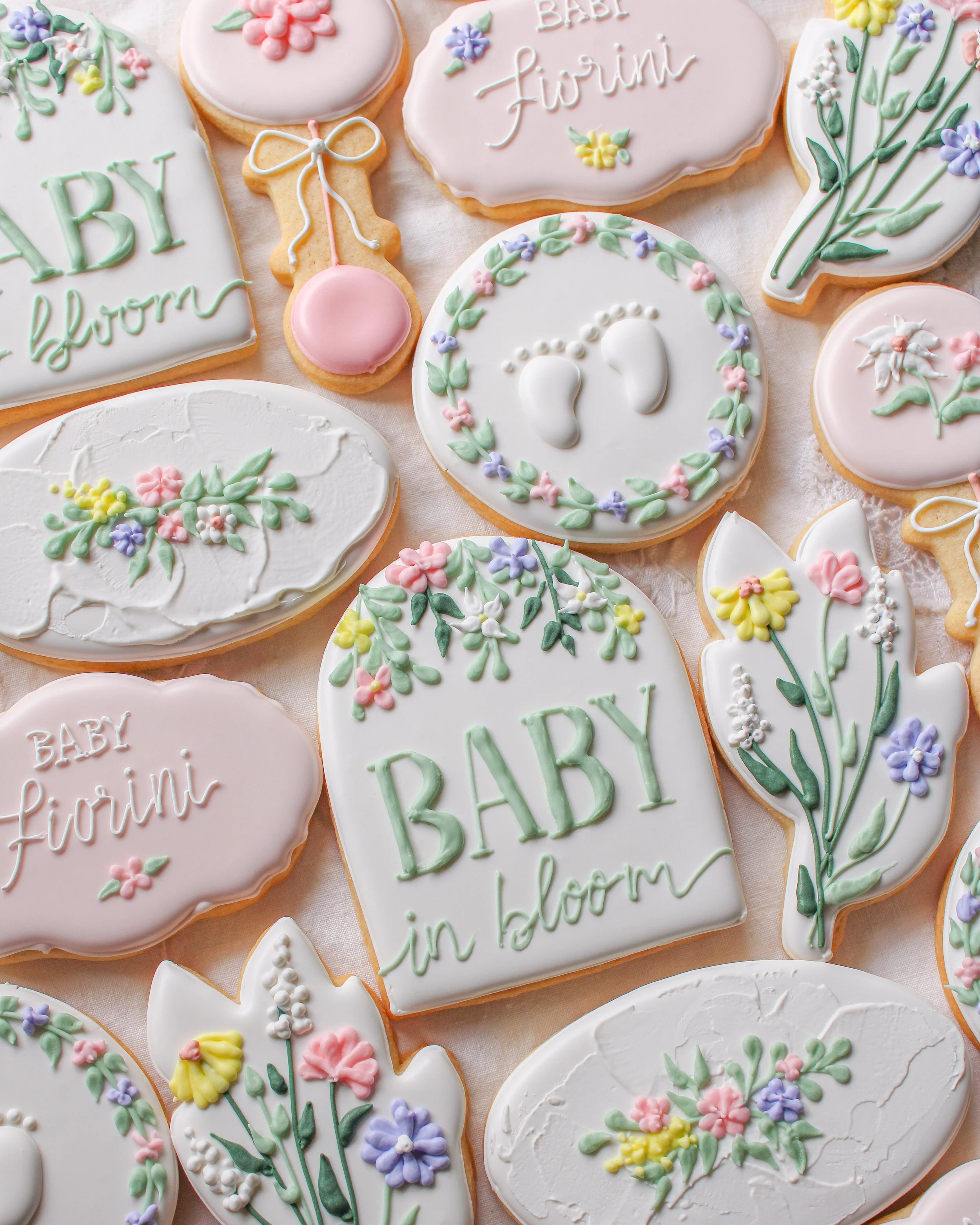 Decorative cookies with pastel icing, floral patterns, and inscriptions such as  "Baby in bloom."