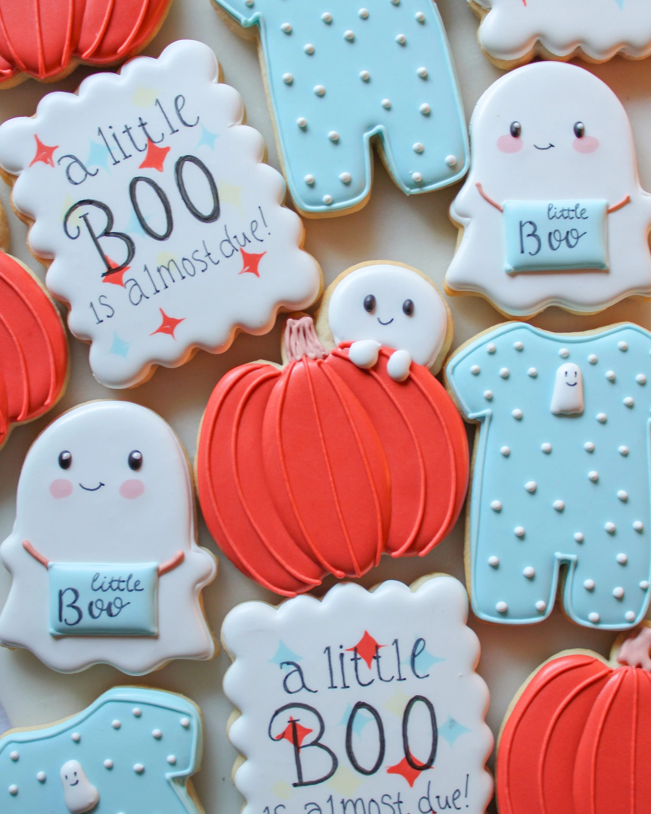 Decorated Halloween baby shower cookies with ghost shapes, pumpkin shapes, and messages like 'a little BOO is almost due!'