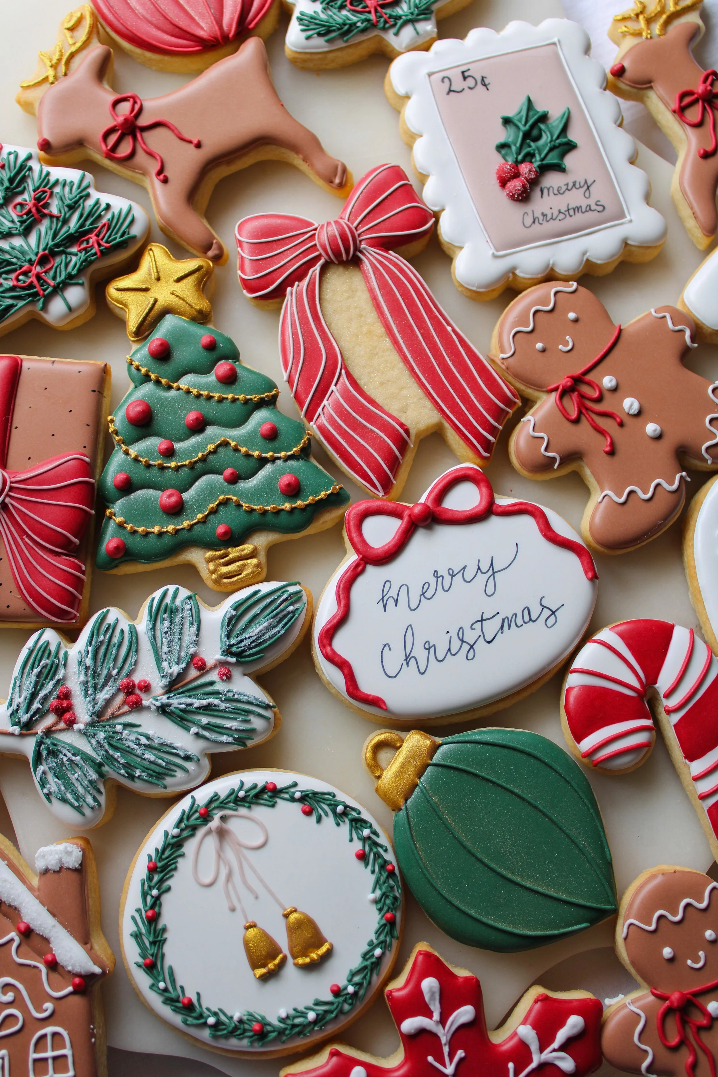 Assortment of decorated Christmas cookies shaped like reindeer, Christmas trees, holly, wreaths, candy canes, bells, and holiday messages, all with festive icing and designs.