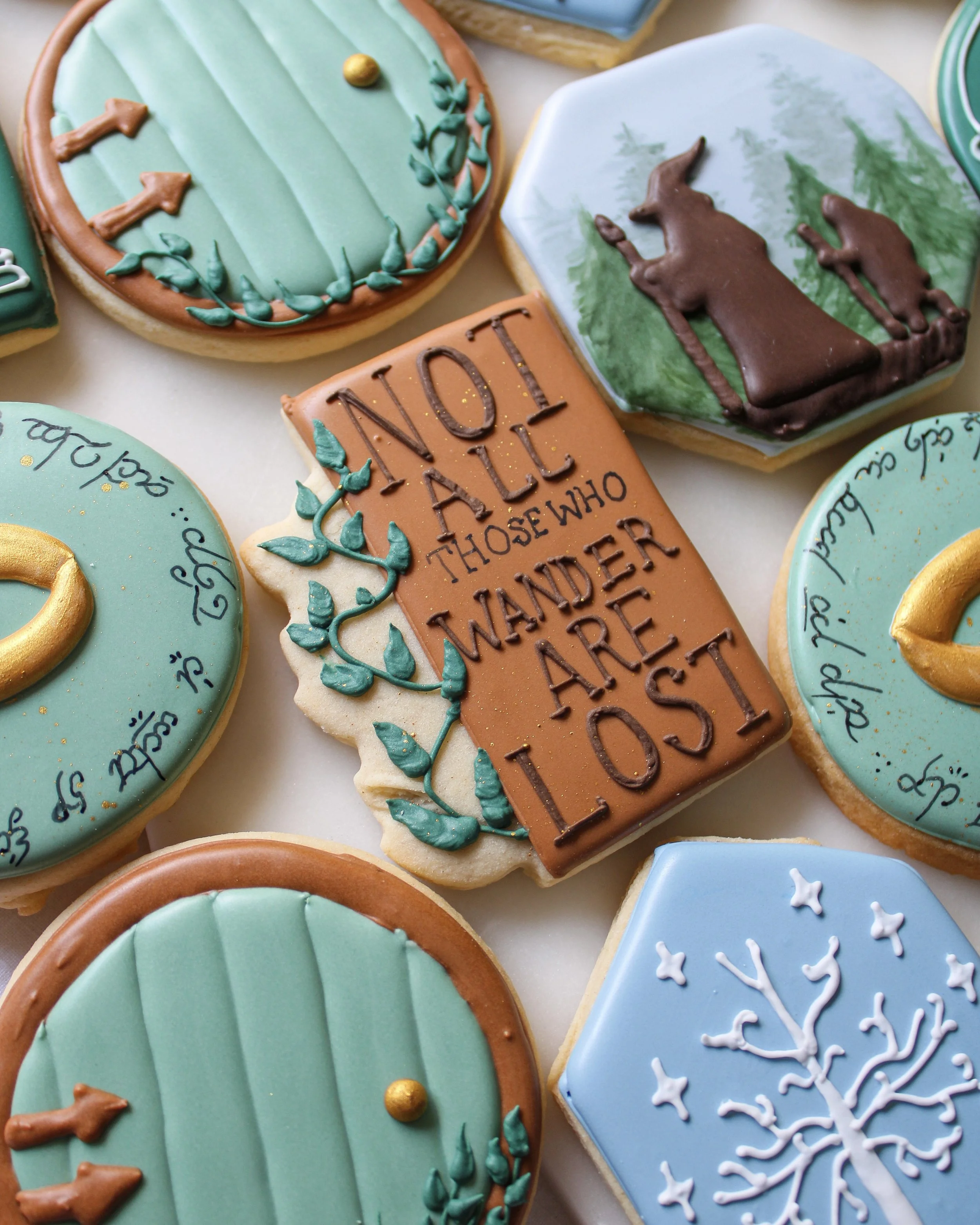 Decorated cookies with a Lord of the Rings theme, including trees, a Gandalf, and a quote that reads 'Not all those who wander are lost'.