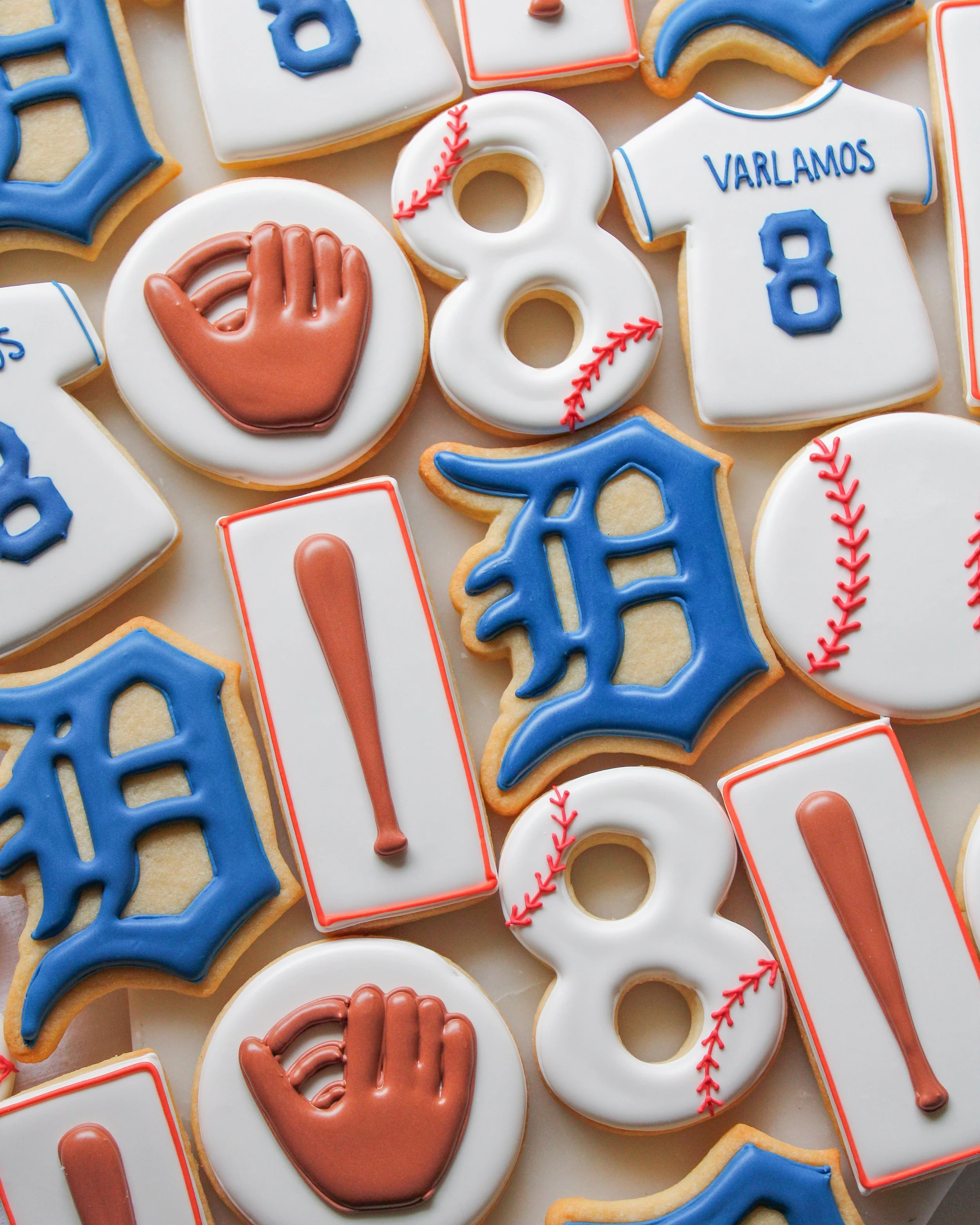 Decorated birthday sugar cookies with Detroit Tigers baseball team themes, including team logo, baseballs, jerseys, and baseball gloves, in red, white, blue, and orange icing.