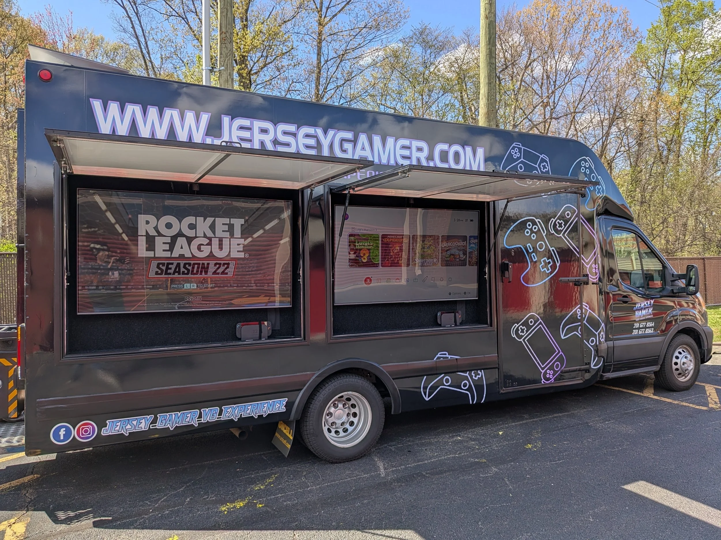 A mobile video gaming truck with blue and black design, featuring the website URL WWW.JERSEYGAMER.COM at the top and a Rocket League Season 22 poster on one side. The truck displays gaming controllers' graphics and social media icons near the bottom.
