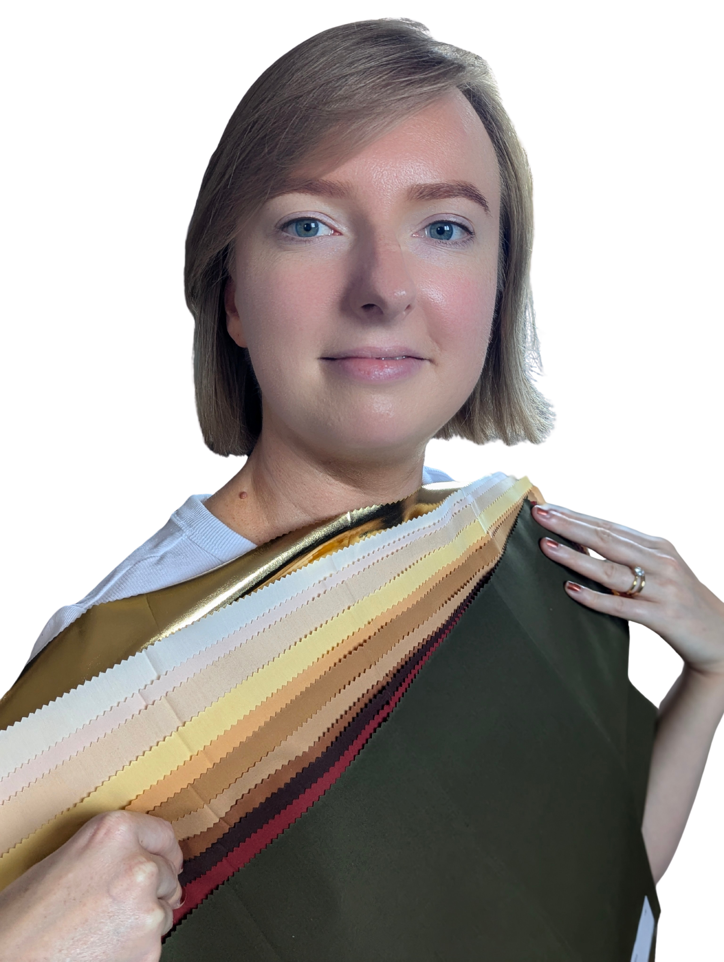 A woman with shoulder-length blonde hair and blue eyes holding a sample swatch book of various fabric or wallpaper colors, standing against a plain black background.