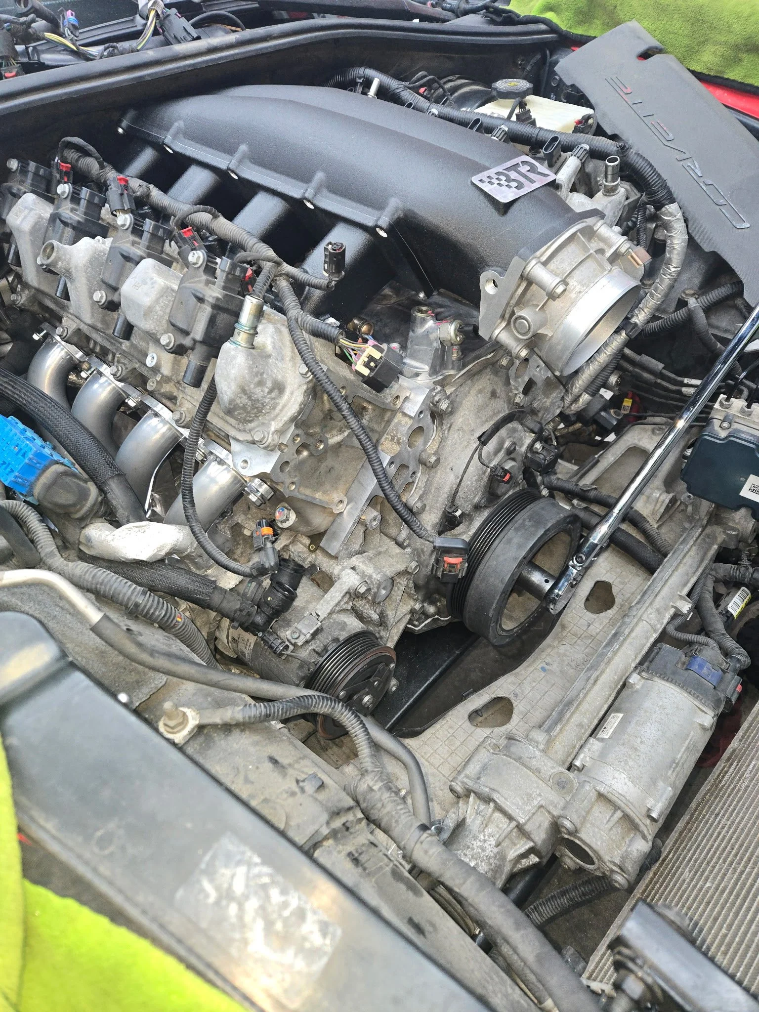 A close-up view of a car engine with various components, belts, and wiring visible.
