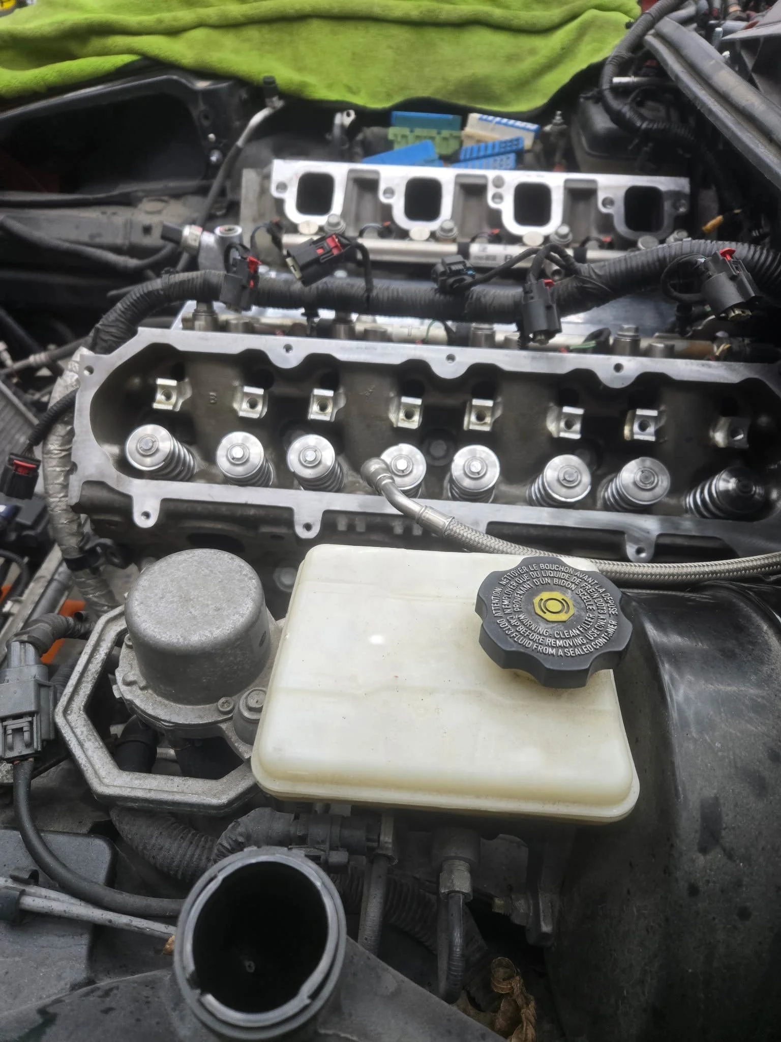 Car engine with removed cylinder head, exposing valve springs and engine components, with a green towel or cloth in background.