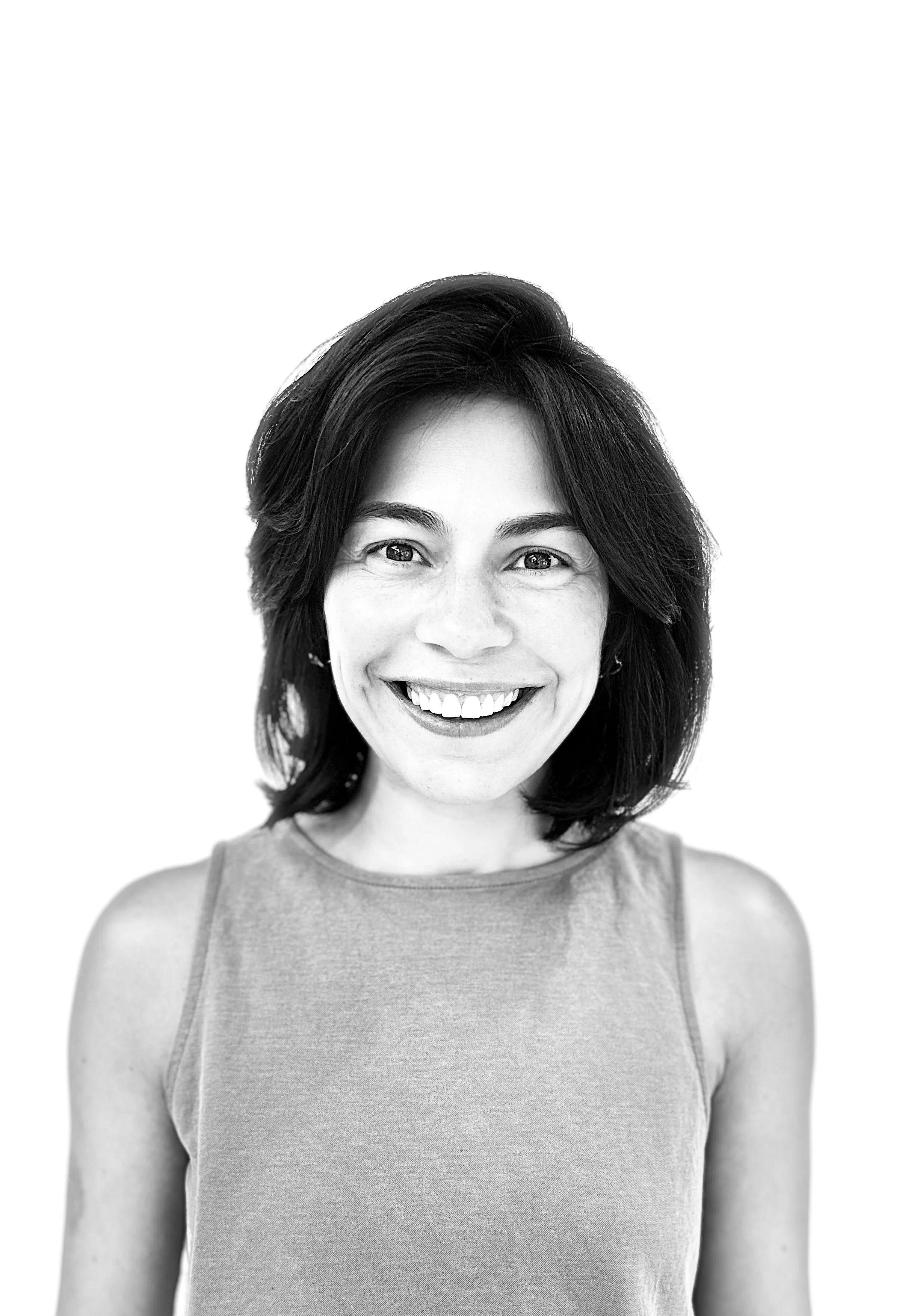 Black and white photo of a woman with shoulder-length dark hair, smiling, wearing a sleeveless top, against a plain white background.