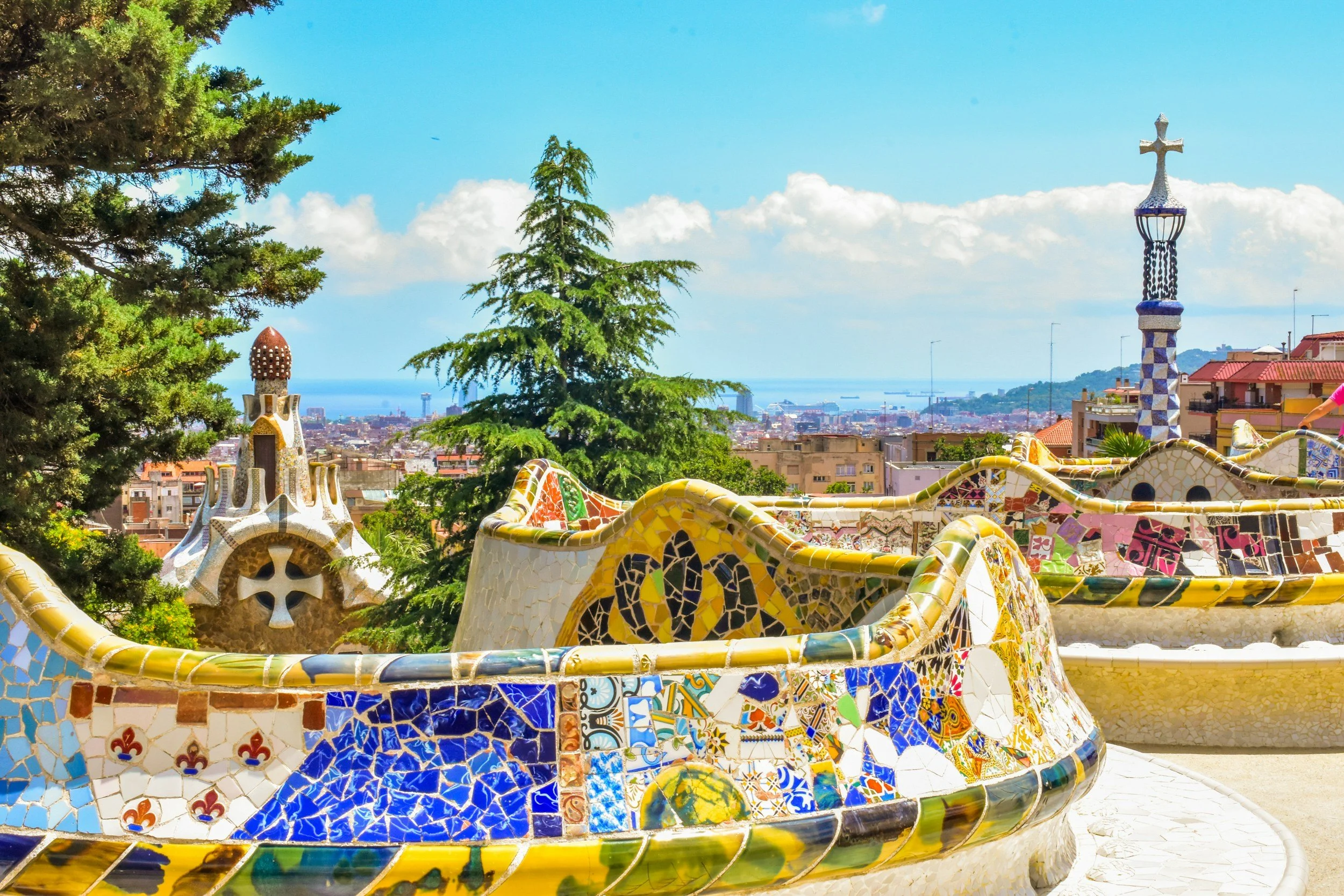 Colorful mosaic terraces at Park Güell in Barcelona with sweeping city views, vibrant tiles, and Gaudí’s iconic architectural details.