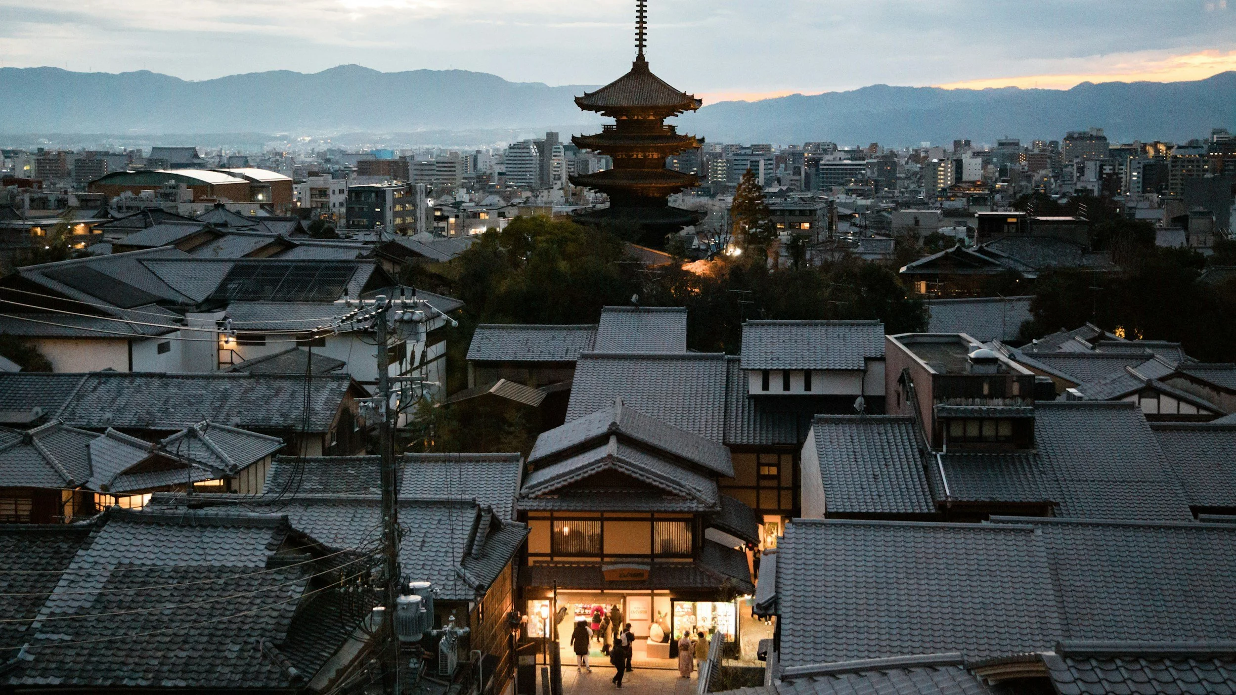 Traditional Kyoto rooftops at dusk with Yasaka Pagoda rising above historic Higashiyama district in Japan