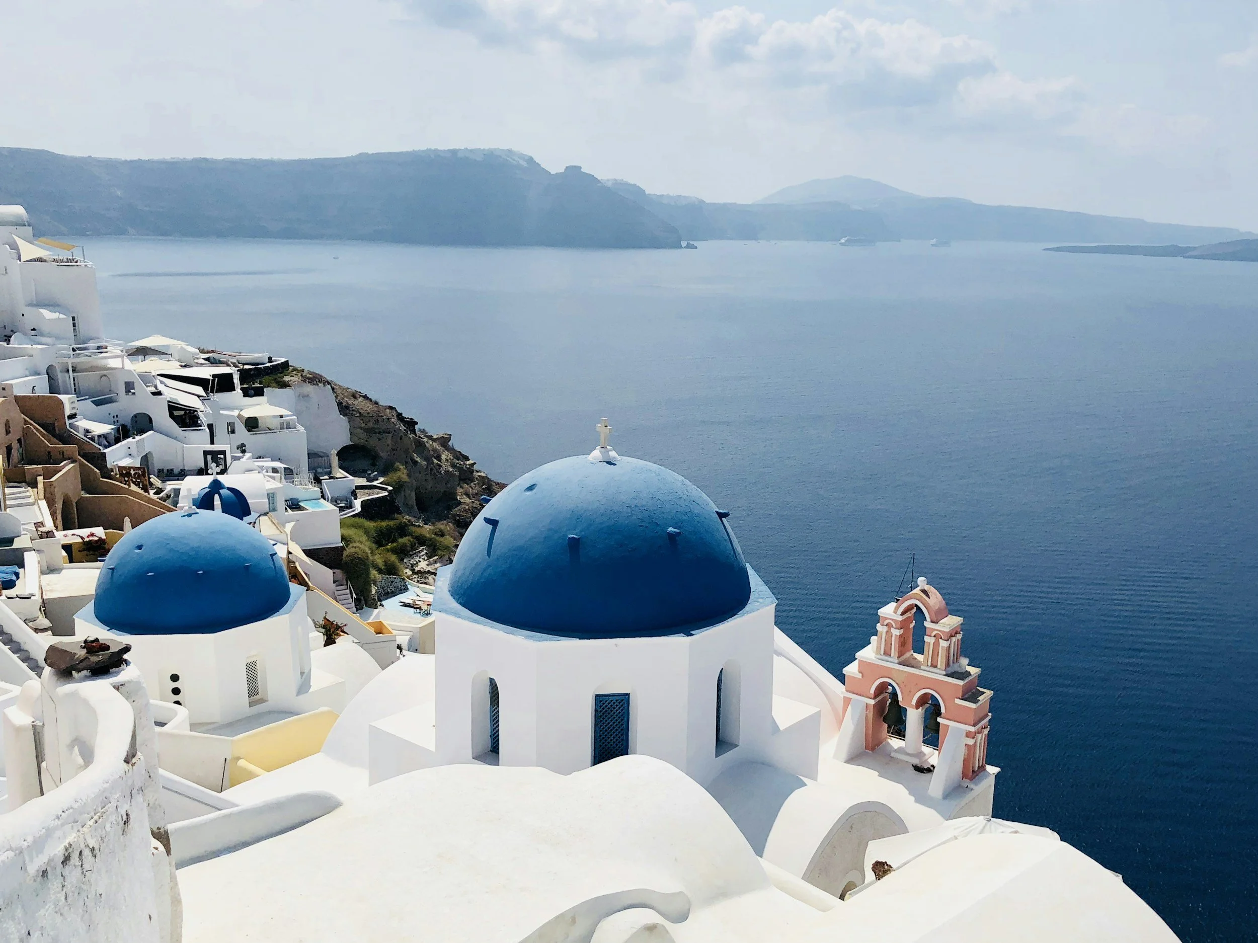 Blue domes of Oia in Santorini overlooking the Aegean Sea with whitewashed buildings and caldera views in Greece