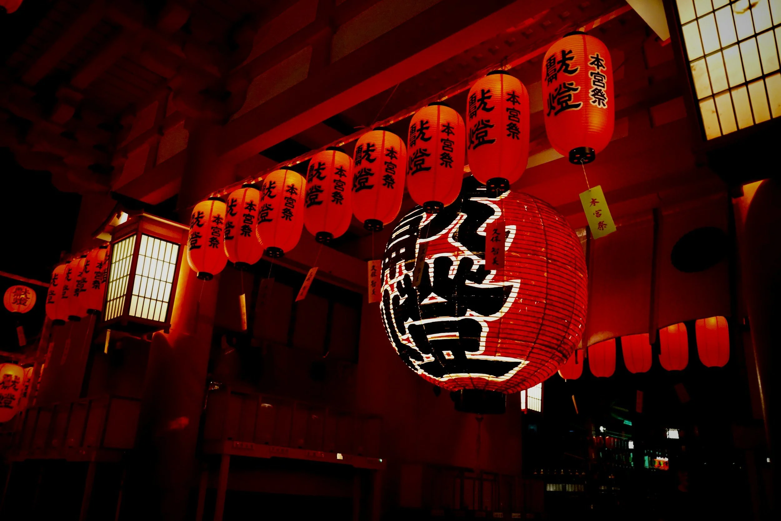 Traditional Japanese red lanterns glowing at night outside a temple in Japan