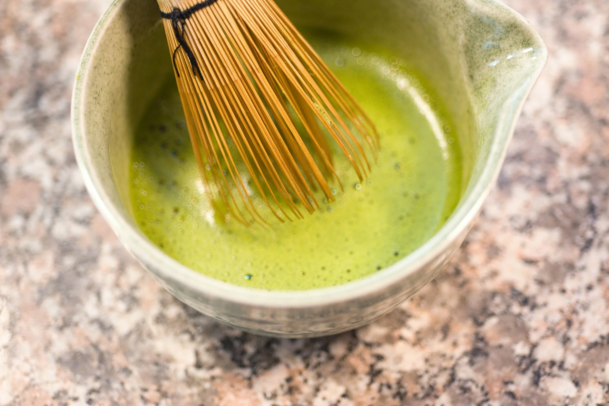 Traditional Japanese matcha being whisked in a bowl with a bamboo chasen