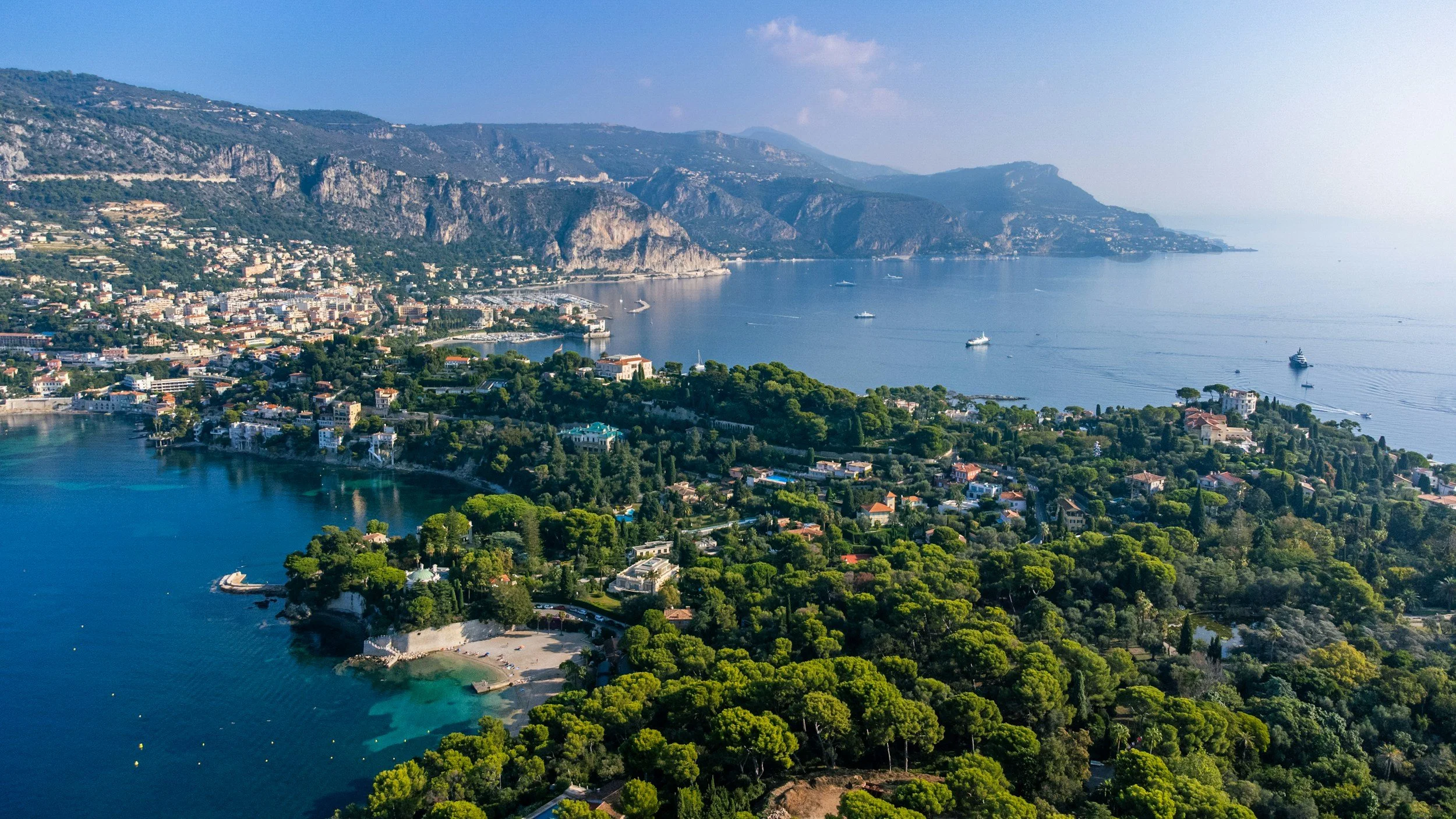 Aerial view of the French Riviera coastline with turquoise water, lush greenery, and seaside villages