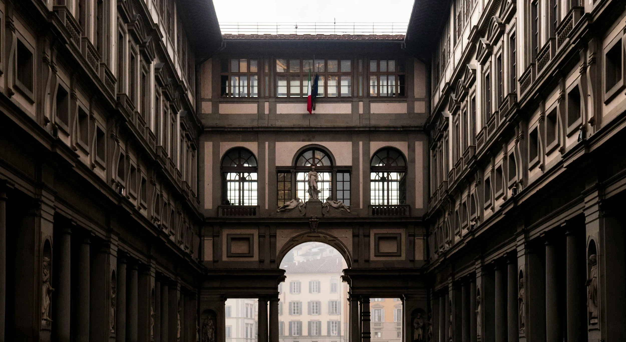 Interior courtyard of the Uffizi Gallery in Florence, Italy, featuring Renaissance architecture, arched windows, columns, and classical statues.