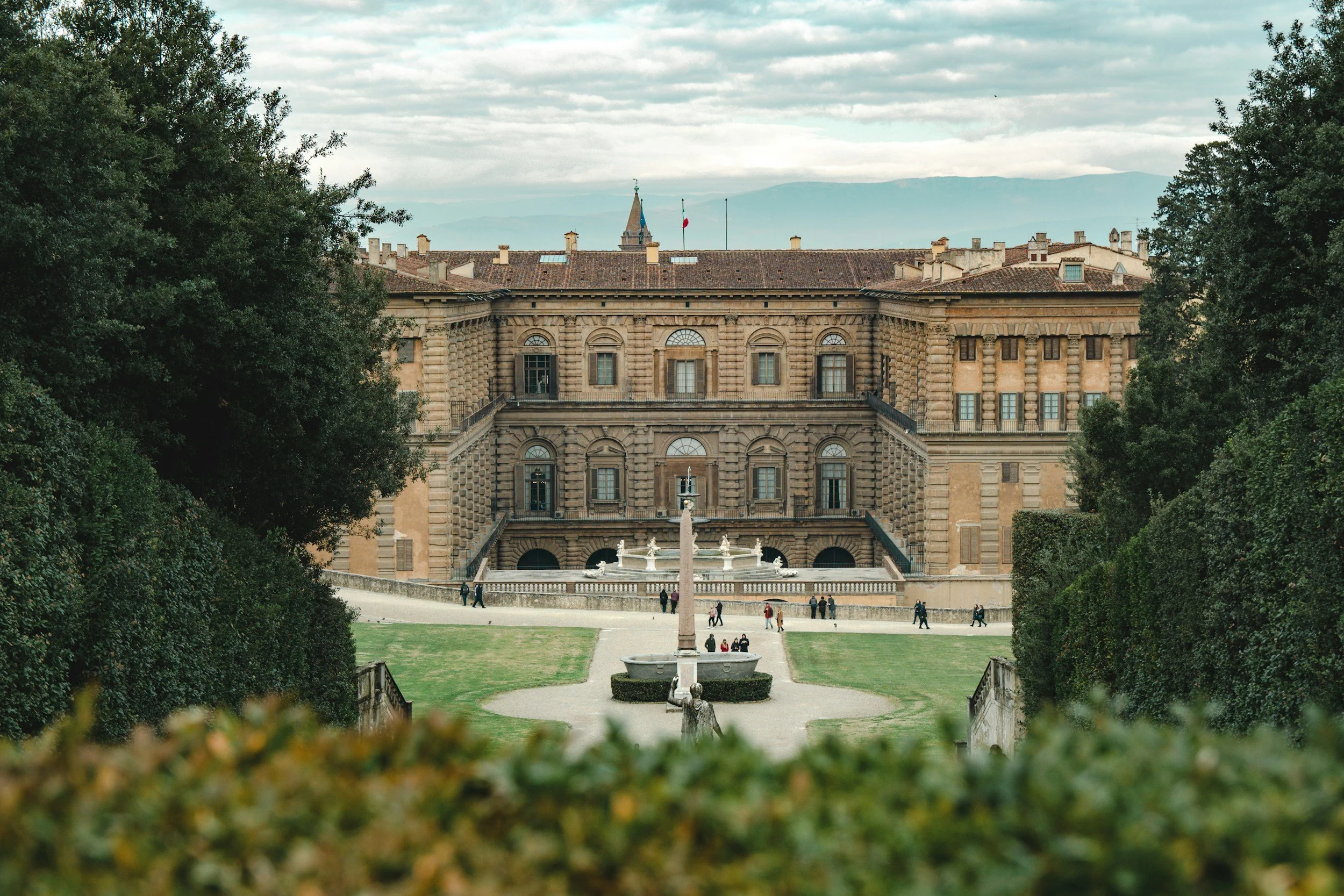 View of Pitti Palace in Florence, Italy, framed by the landscaped greenery and fountains of the Boboli Gardens.