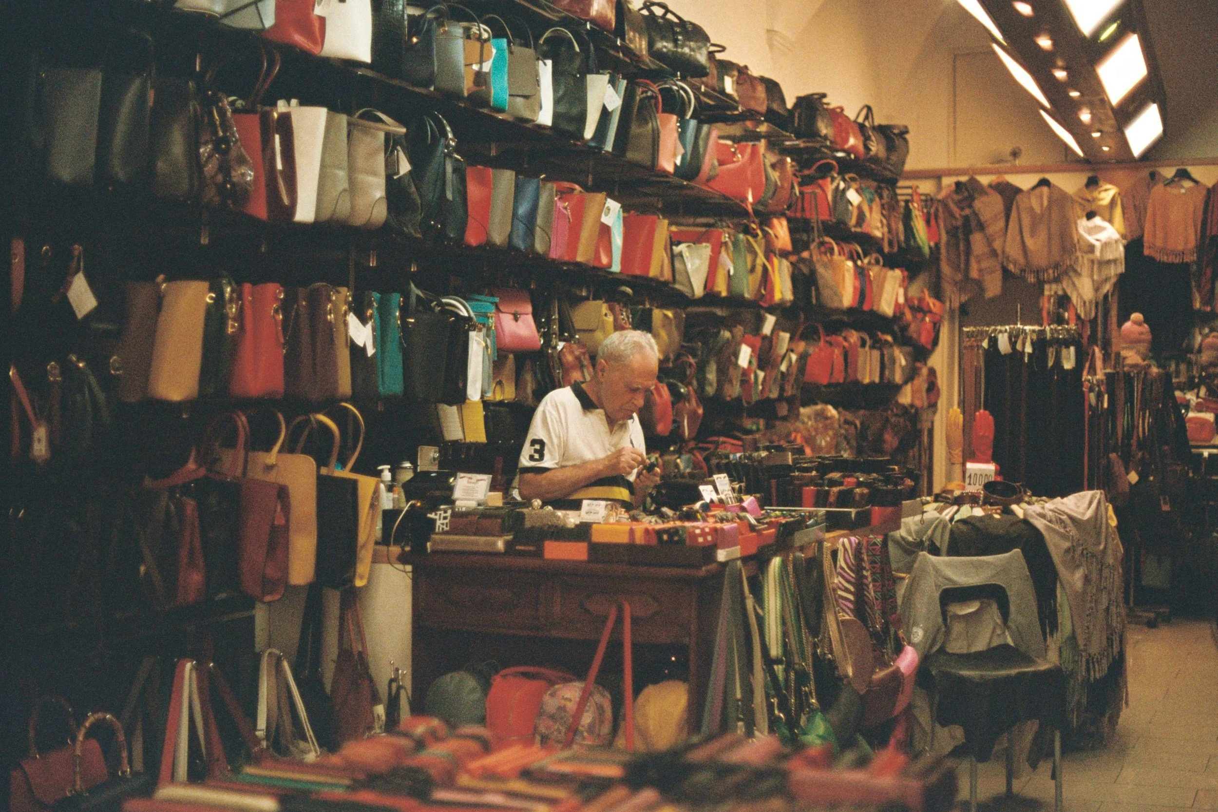 Interior of a traditional leather shop in Florence, Italy, filled with colorful handcrafted handbags, wallets, belts, and accessories.