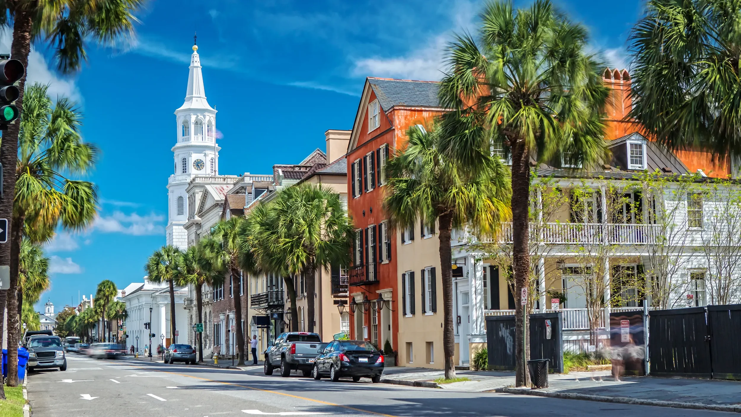 Historic downtown Charleston, South Carolina with colorful homes, palm-lined streets, and the iconic church steeple in the background