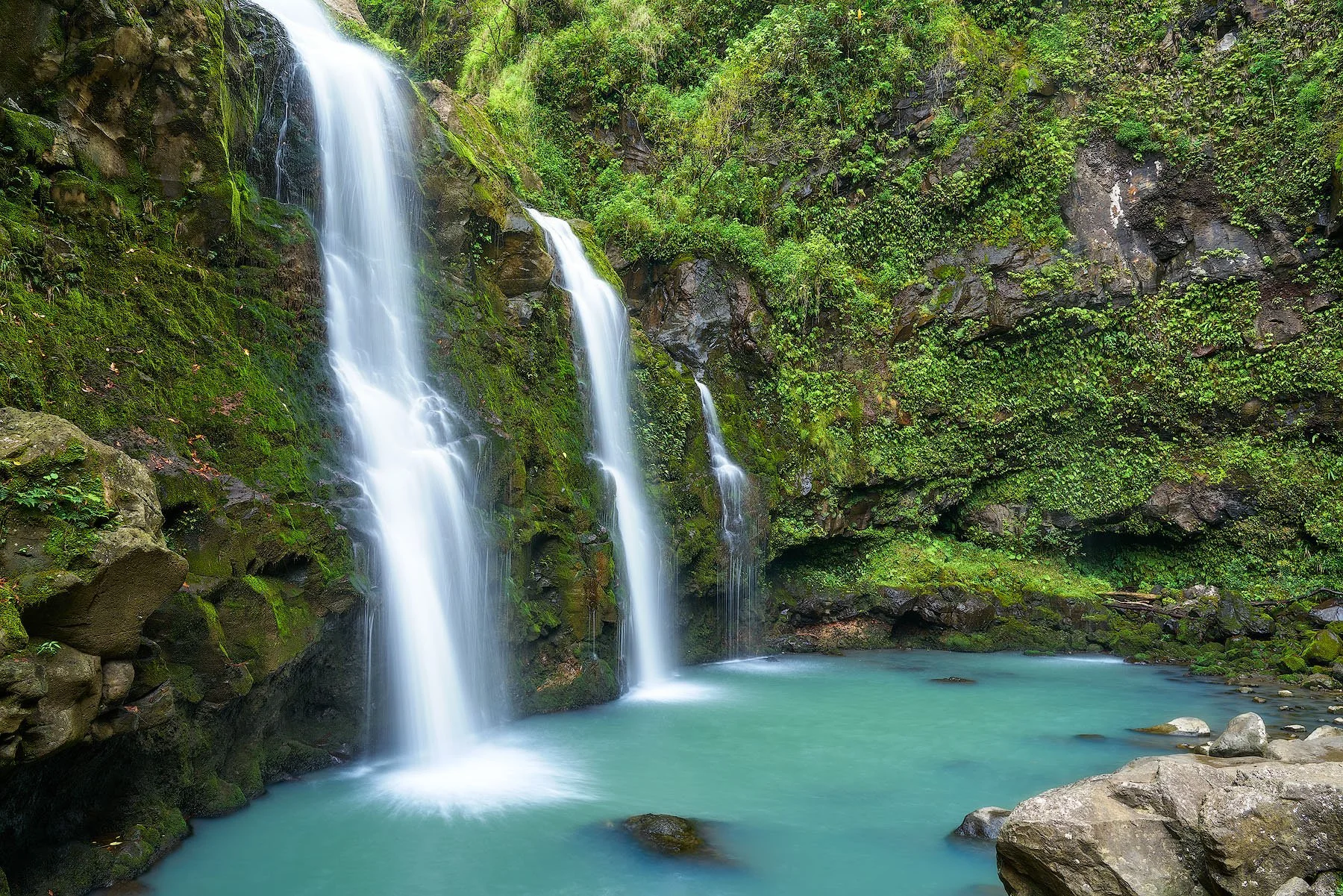 Three Bears Waterfall in Hana, Maui with cascading waterfalls flowing into a turquoise pool surrounded by lush tropical greenery