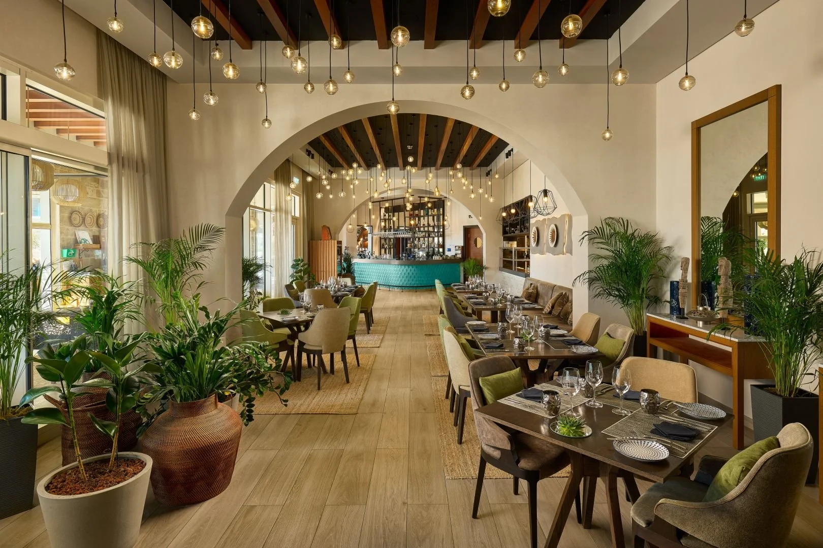 Elegant dining room at The Spot restaurant at The Chedi Luštica Bay in Montenegro, featuring Mediterranean-inspired design, warm wood accents, lush greenery, arched architecture, and sophisticated indoor seating.