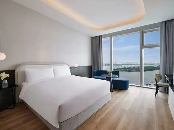 River view guest room at Naru Ambassador Hotel Seoul featuring a king bed, modern minimalist design, and floor-to-ceiling windows overlooking the Han River.