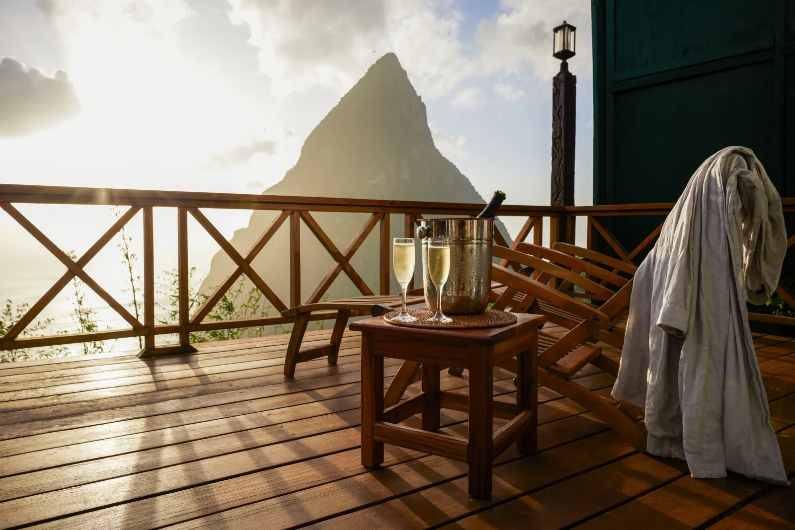 Romantic private terrace at a luxury resort in Saint Lucia, featuring champagne, wooden lounge chairs, and breathtaking sunset views of Petit Piton and the Caribbean Sea.